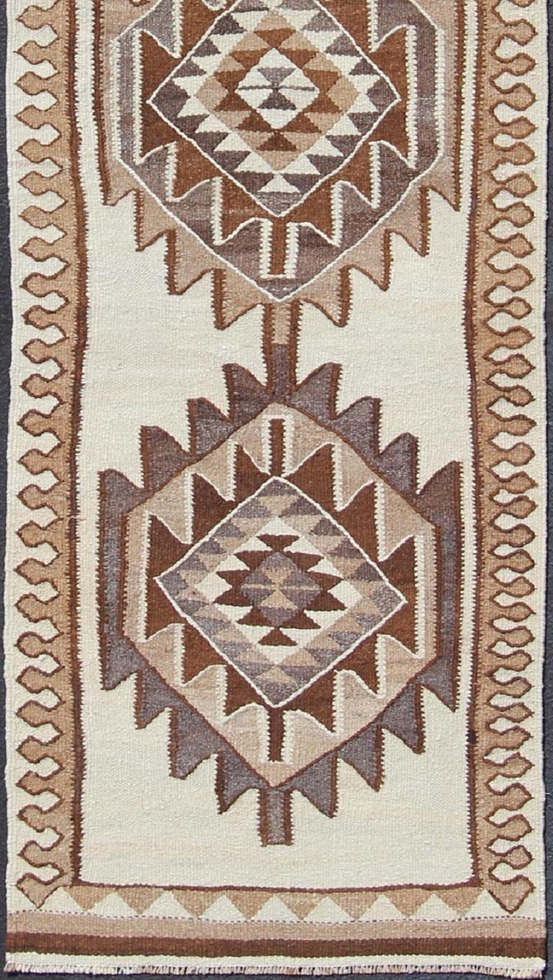 Brown and cream colored tribal Medallion design Kilim Turkish vintage runner, rug en-176528, country of origin / type: Turkey / Kilim, circa 1960.

This unique Turkish Kilim runner features a graphic vertical design of interconnected medallion