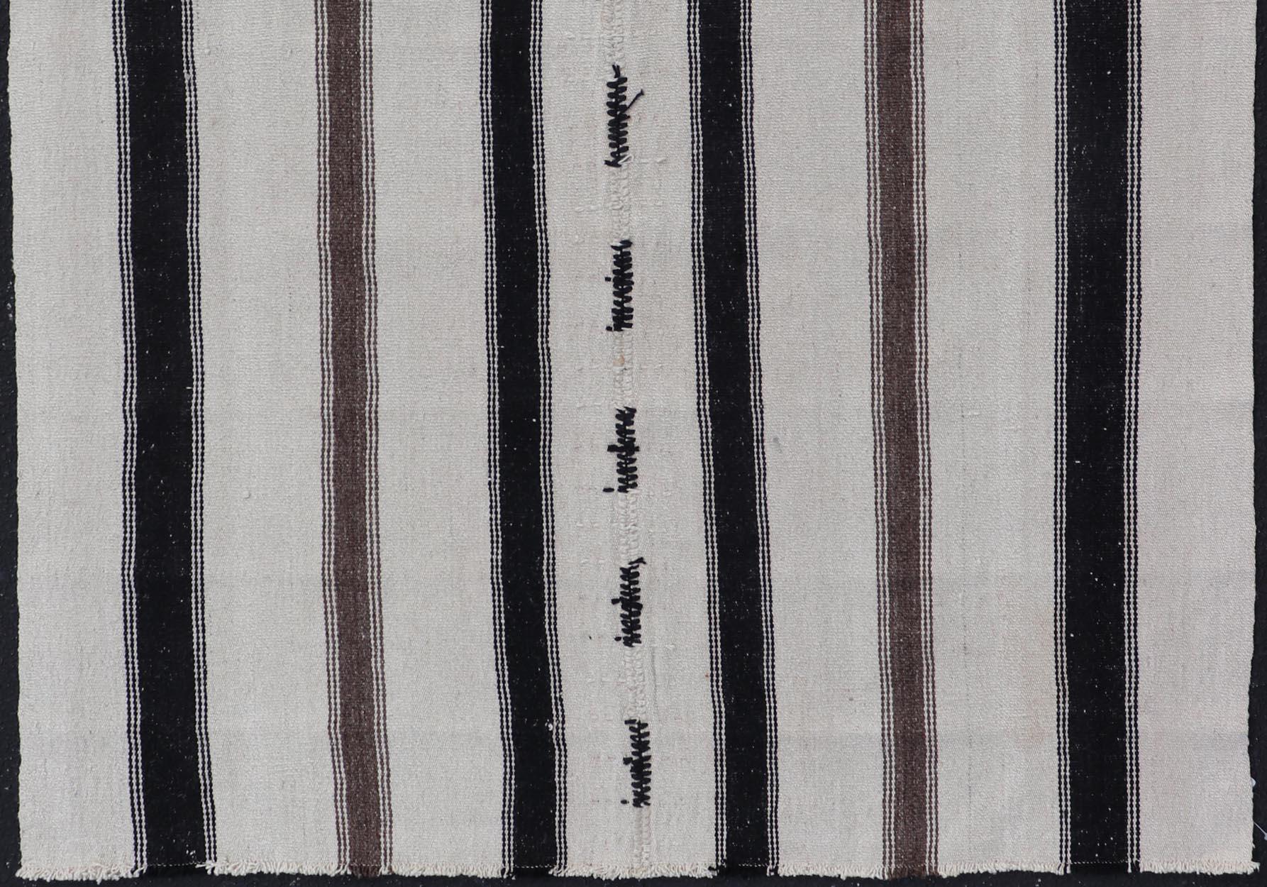 Measures: 4'4 x 6'10 

This vintage Turkish Kilim features simple design and neutral colors, giving these types of rugs a rise in popularity in modern interiors of the 2020's. The paneled stripes feature ebony, cream, and browns, in a very minimal
