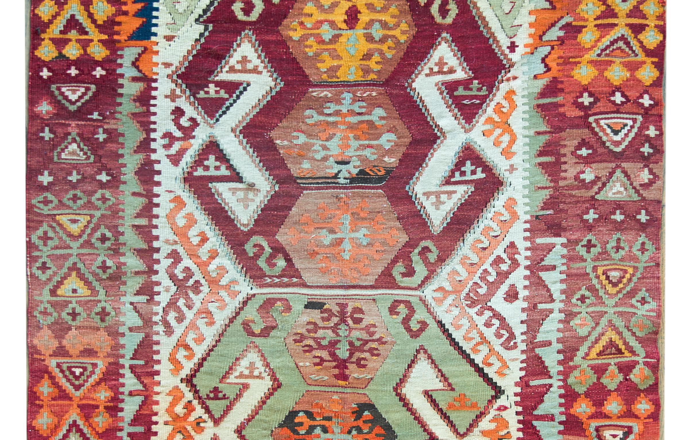 An incredible and bold mid-20th century Turkish Konya kilim rug with two large geometric pattered medallion with myriad styled flowers and surrounded by a fantastic border with more stylized flowers and geometric shapes, and all woven in bright