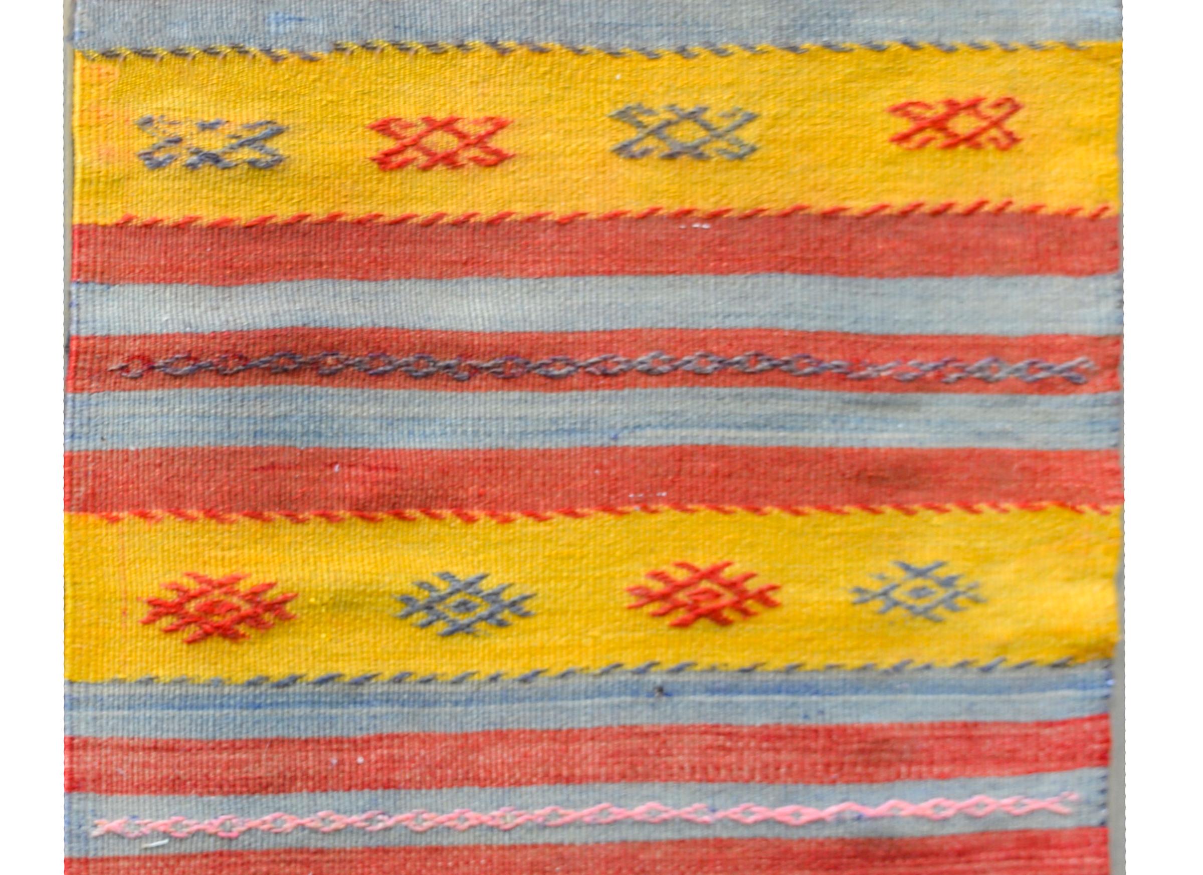 A beautiful vintage Turkish Konya Kilim runner composed with multiple stripes woven in crimson, indigo, gold, and pink and with embroidered stylized flowers.