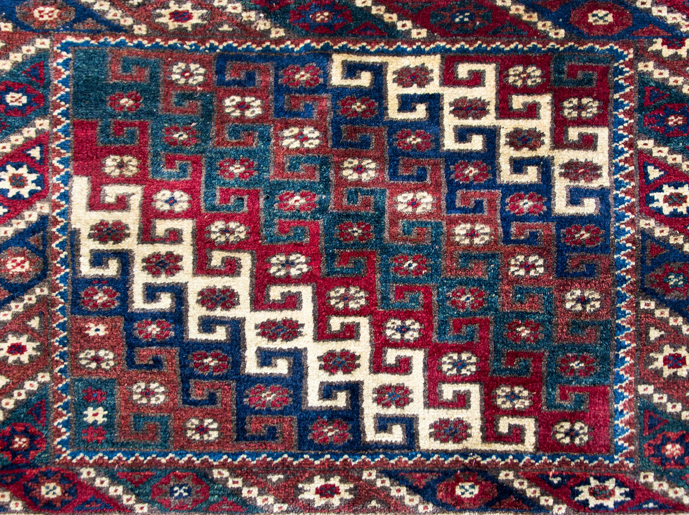 A beautiful vintage Turkish Konya rug with an all-over diagonal pattern with interlocking geometric stripes and petite flowers, surrounded by a border with more petite flowers and geometric patterned stripes, and all woven in jewel tones including