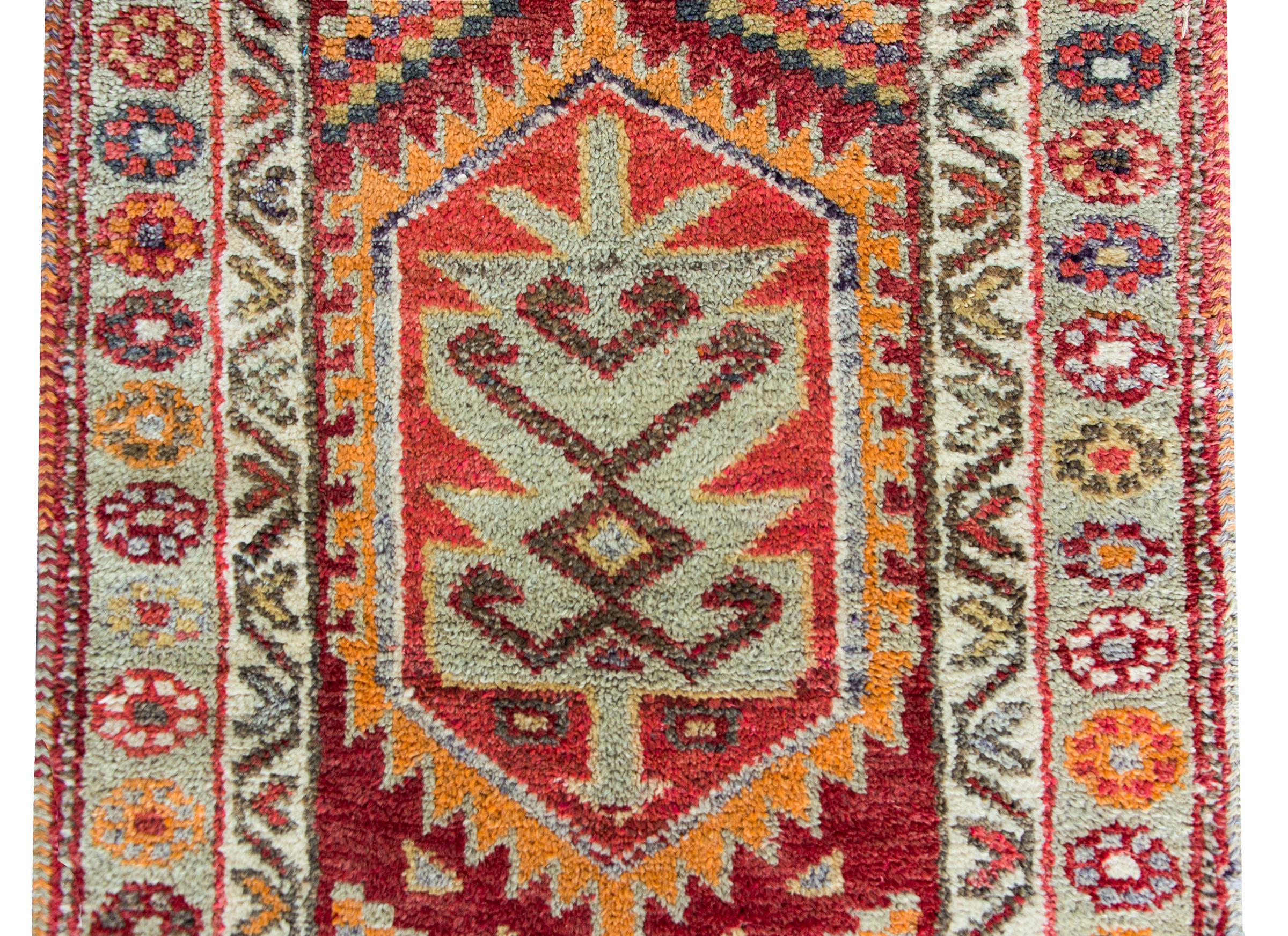 A gorgeous Mid-20th Century Turkish Konya runner with the best Large Scale stylized flowers and geometric shapes woven in brilliant crimsons, oranges, light indigos, pinks, and whites, and surrounded by a border with more smaller stylized flowers.