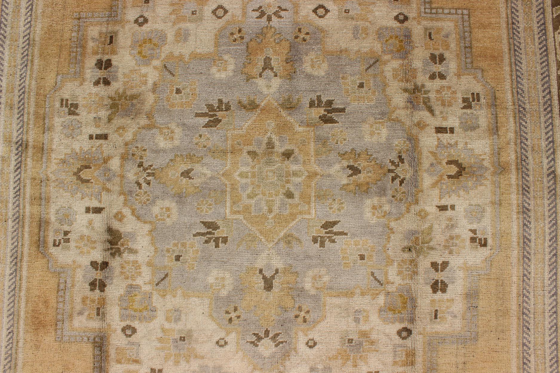 Maße: 6'8 x 12

Dieser türkische Oushak im Vintage-Stil zeichnet sich durch ein kühnes Design aus, das durch einzigartige, helle Farbtöne gemildert wird. Die Umrandung ist schokoladenbraun und enthält Ranken und Blumen. Zu den Farben gehören Gold,