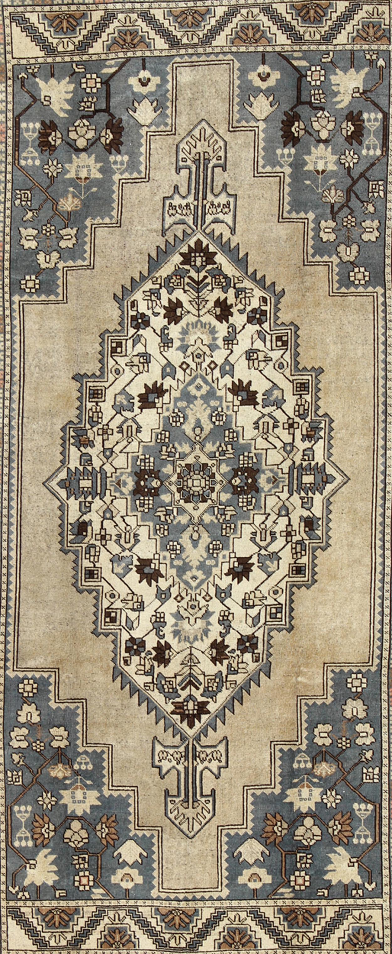 Measures: 7'2 x 12'9

Unique in its color palette and composition, this vintage Oushak features large-scale motifs and a central medallion. The field design is rendered in muddy blue, sandy taupe, chocolate brown, and cream. The wide-band mocha