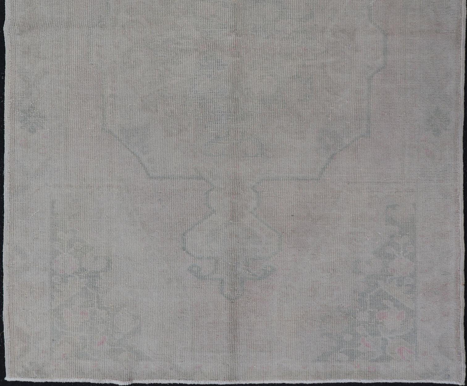 Measures 4'5 x 7'0 

The taupe-sandy color field homes a muted central medallion decorated in muted blue and pink. Tones of faded light green can be found within the details of the field. 

Country of Origin: Turkey; Type: Oushak; Design: