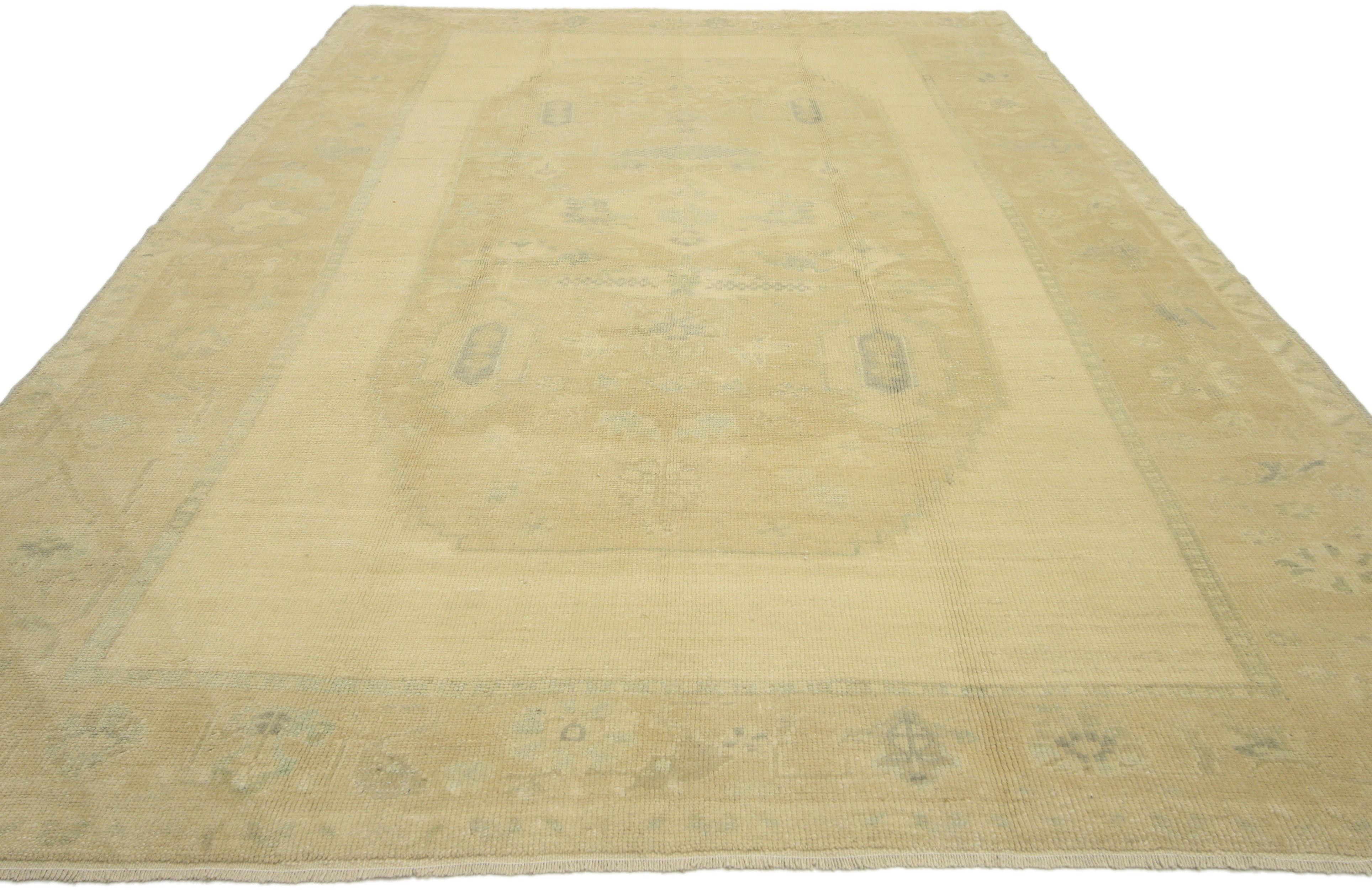 51343, vintage Turkish Oushak area rug with muted washed out colors. This hand-knotted wool vintage Turkish Oushak area rug features a large stair-step medallion filled with an array of blooming palmettes, geometric motifs and stylized florals. The