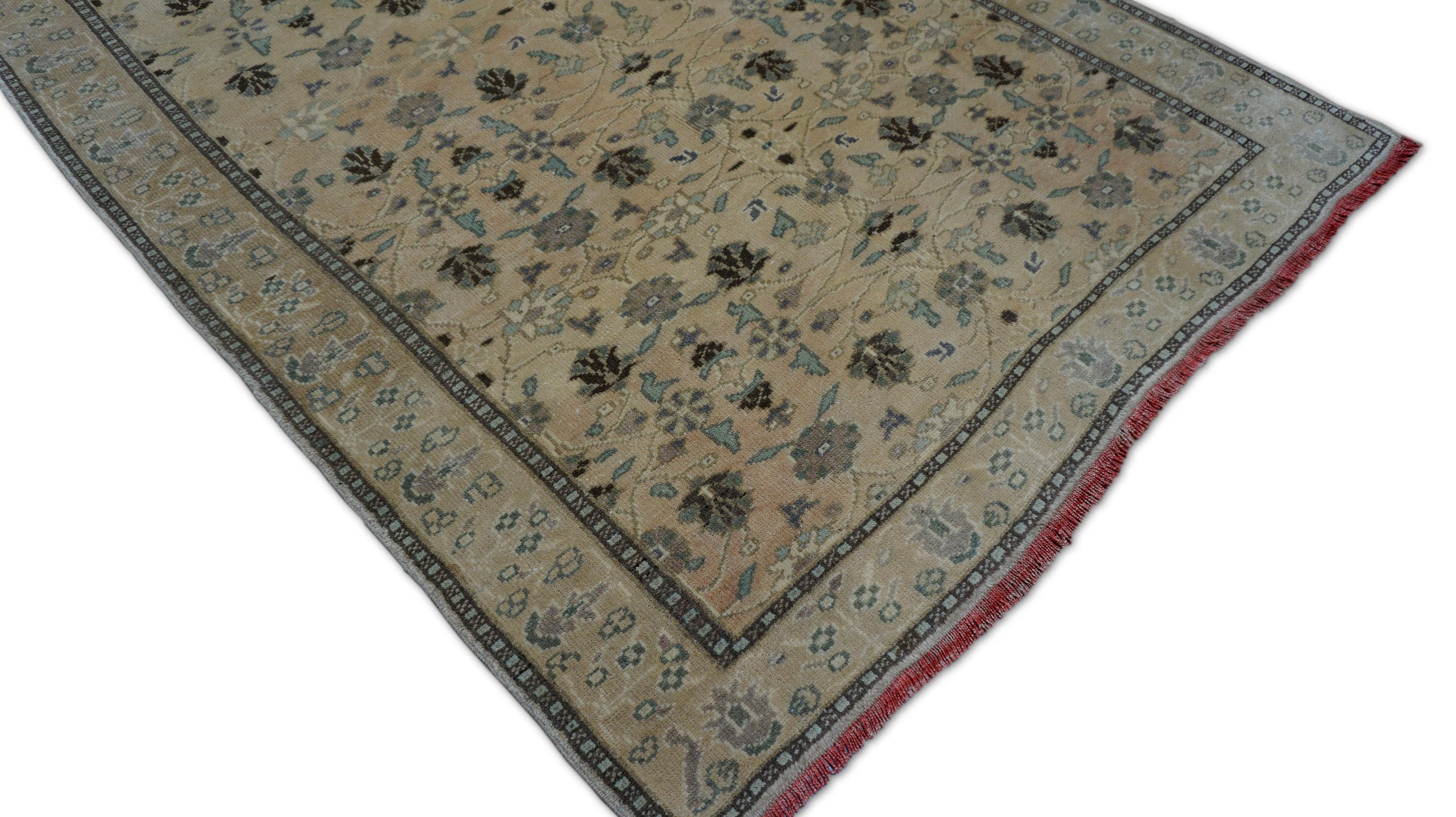 This elegant hand-knotted wool rug is a refined example of the region’s storied Oushak weaving tradition. Rendered in a muted palette of beige, green, and brown, the rug features a soft all-over floral pattern with stylized palmettes and delicate