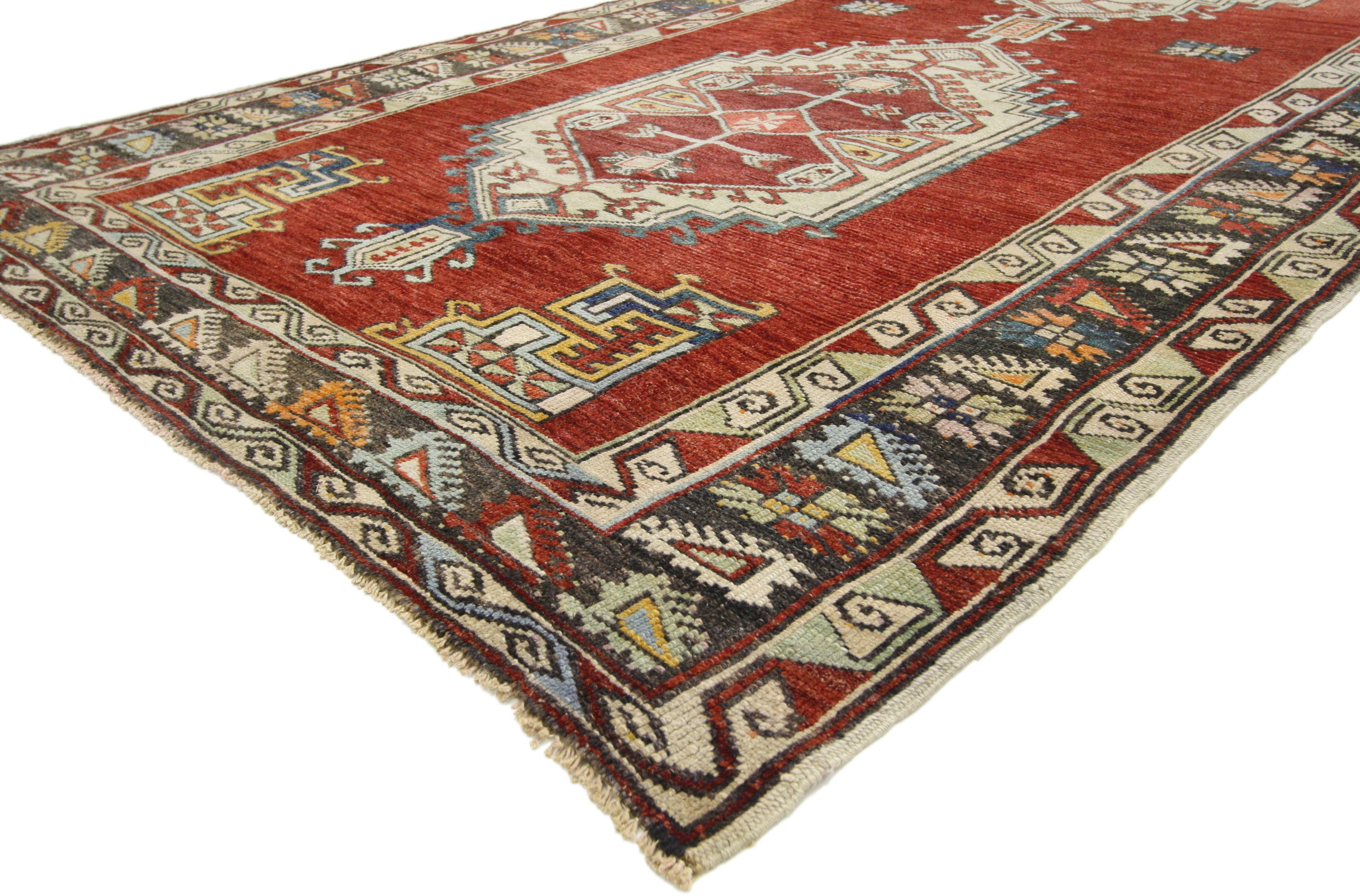 52418, vintage Turkish Oushak Gallery rug, wide hallway runner. This hand knotted wool vintage Turkish Oushak Gallery rug features two hexagonal medallions with latch hook edges and finials against a red abrash backdrop. Angular geometric spandrels