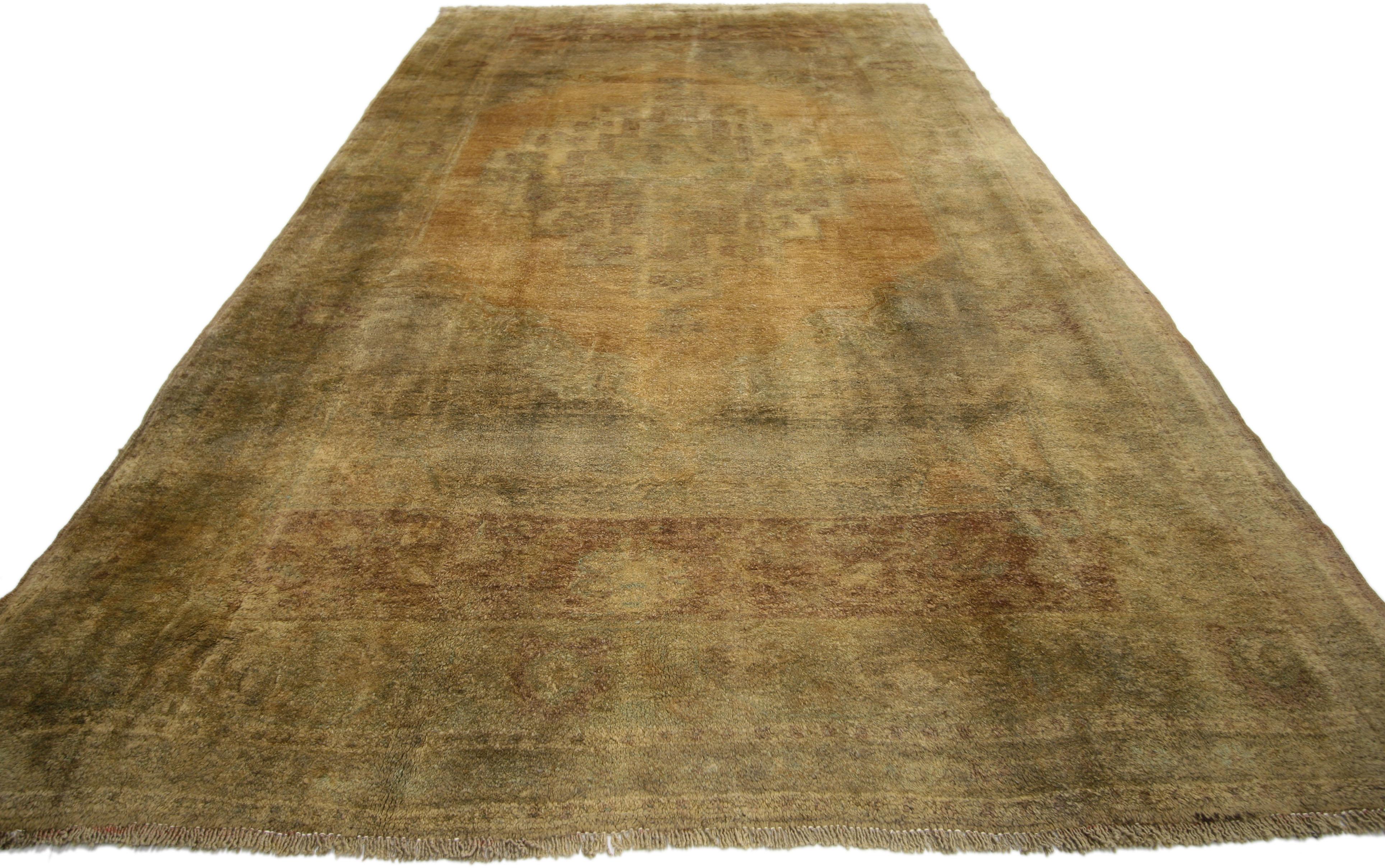 74106, tapis turc Oushak vintage de style Mission et aux tons chauds de la terre. Ce tapis galerie turc vintage en laine noué à la main présente un médaillon central discret dans un champ de chameaux dorés abrasés. Il est entouré d'écoinçons neutres