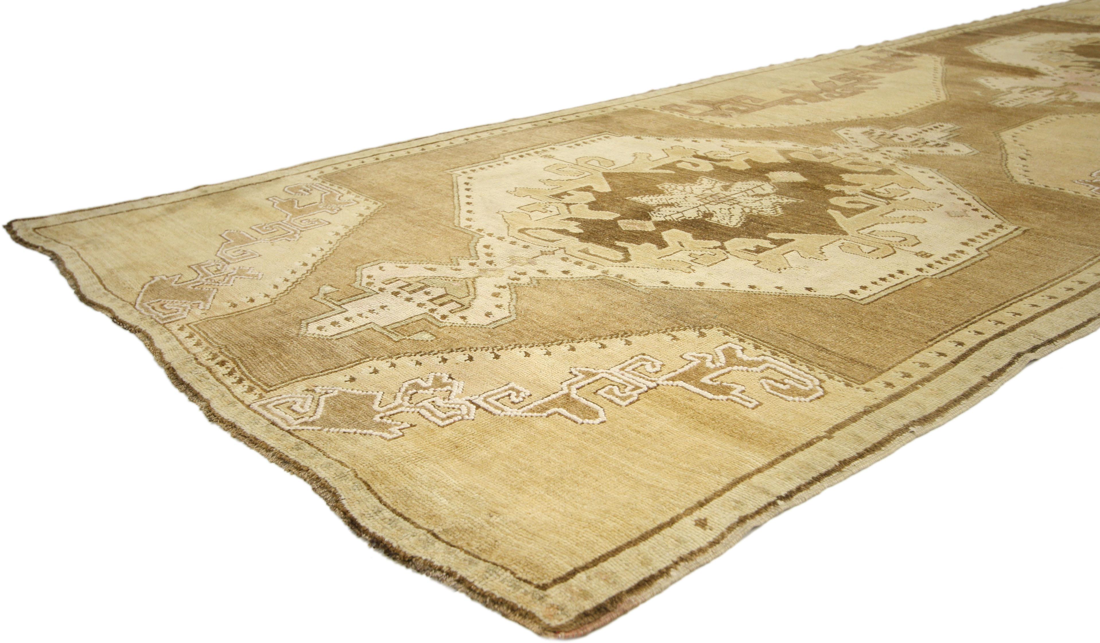 50581, vintage Turkish Oushak gallery rug with mission style, wide hallway runner. With two grandeur medallions and a captivating composition enhanced by its rich waves of abrash and lustrous wool, this vintage Oushak carpet runner is a timeless