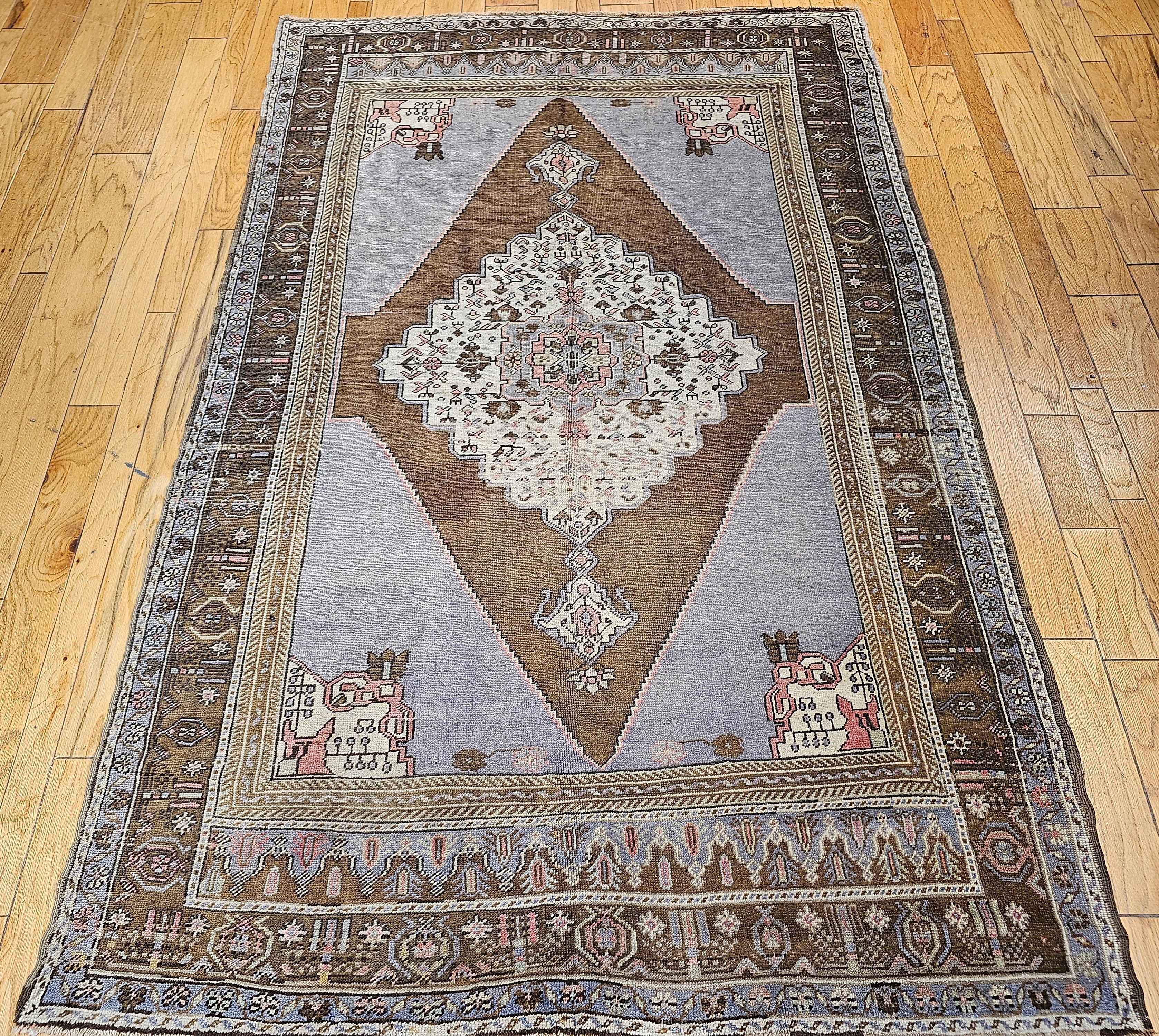 A beautiful vintage Turkish Oushak room size rug in a geometric medallion pattern in pale blue, brown, ivory, lavender, and pink colors from the early 20th century.  The rug has an open field design resembling Persian Bidjar and Serapi carpets.  