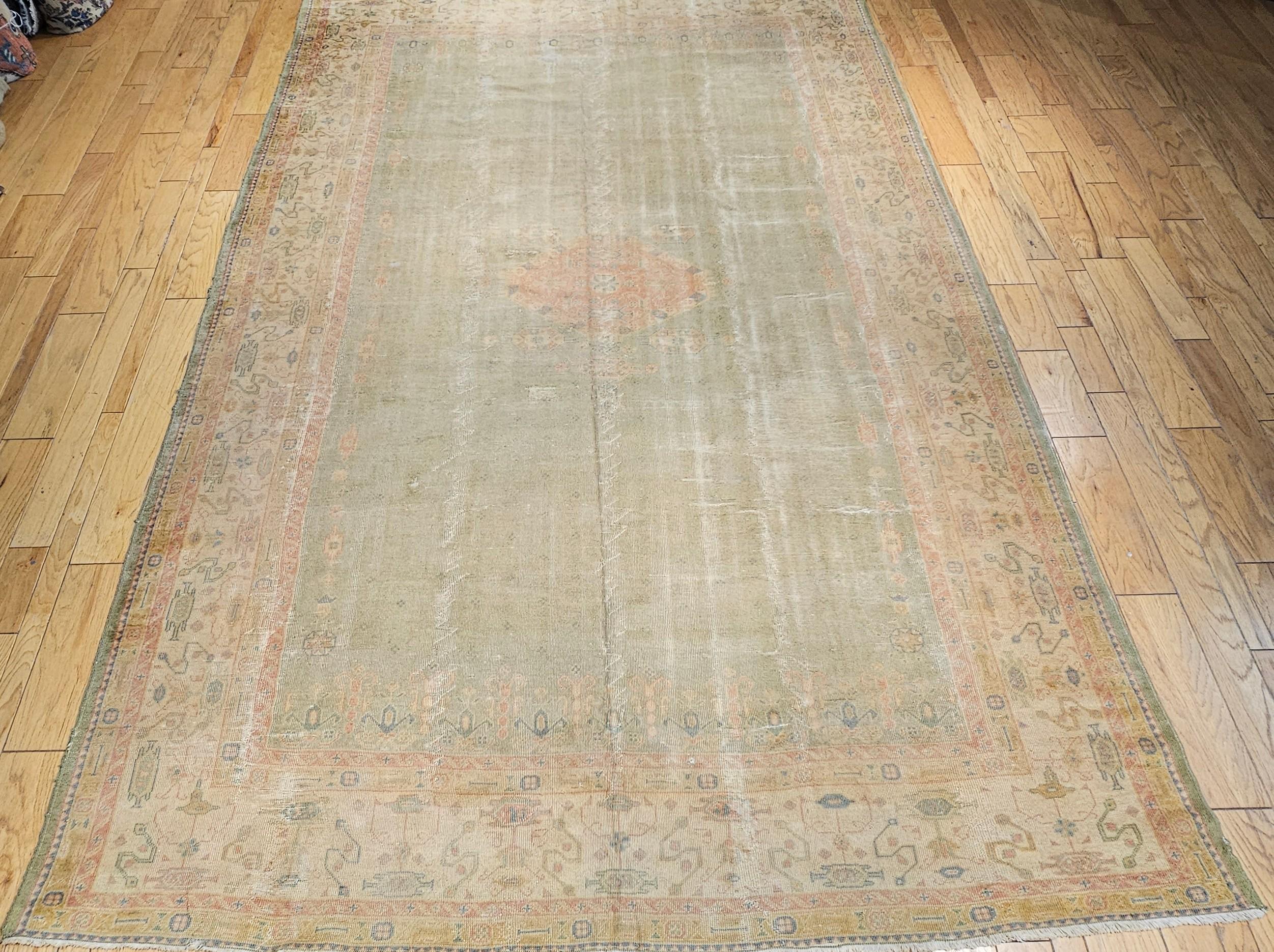 Vintage room size Turkish Oushak in an open geometric pattern in pale green, yellow, and pink colors from the early 20th century. The rug has an all-over design with a very small central medallion set in a pale green color field with geometric