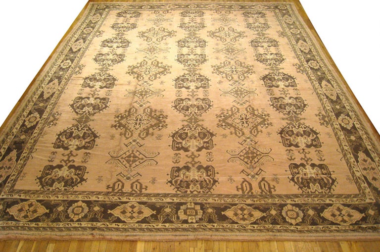 Vintage Turkish Oushak oriental rug, size 17'4 H x 13'5 W, circa 1940.  This hand-knotted semi-antique wool Turkish carpet features a repeating 'crab' design in its softly hued central field, the colors of which are reciprocated in the handsome