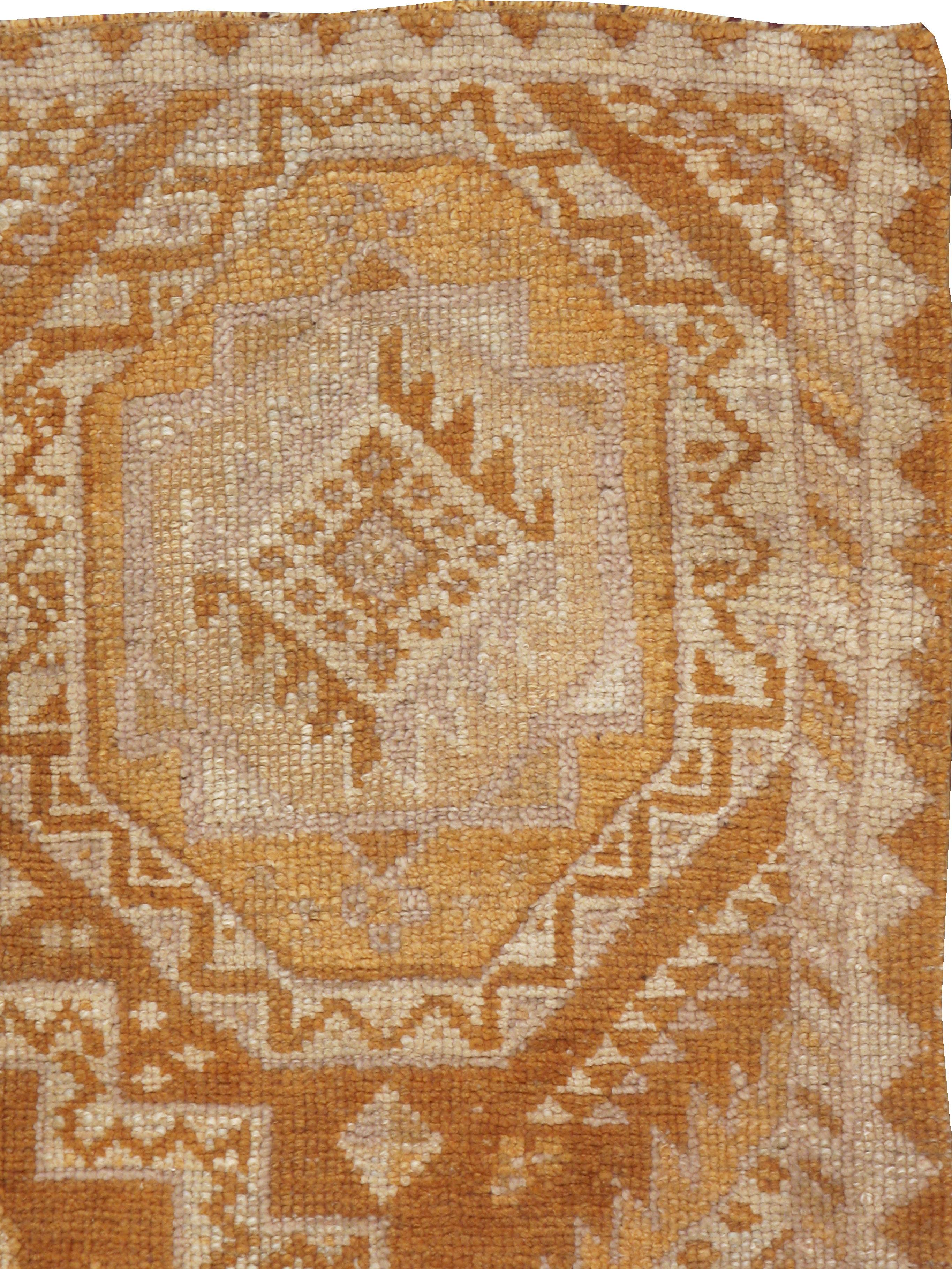 A vintage Turkish Oushak rug from the mid-20th century. A stepped central cross is closely fitted into a field with four enormous octagons and lateral sawtooth triangles in this vintage rug. The pattern is incredibly strong, but the soft rust and