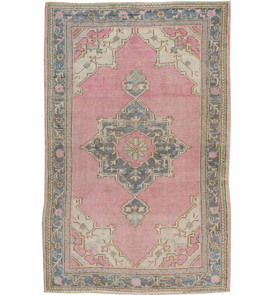 A vintage Turkish Oushak throw rug handmade during the mid-20th century with a dusty rose pink field and blue-grey octagram medallion and border.

Measures: 3' 7