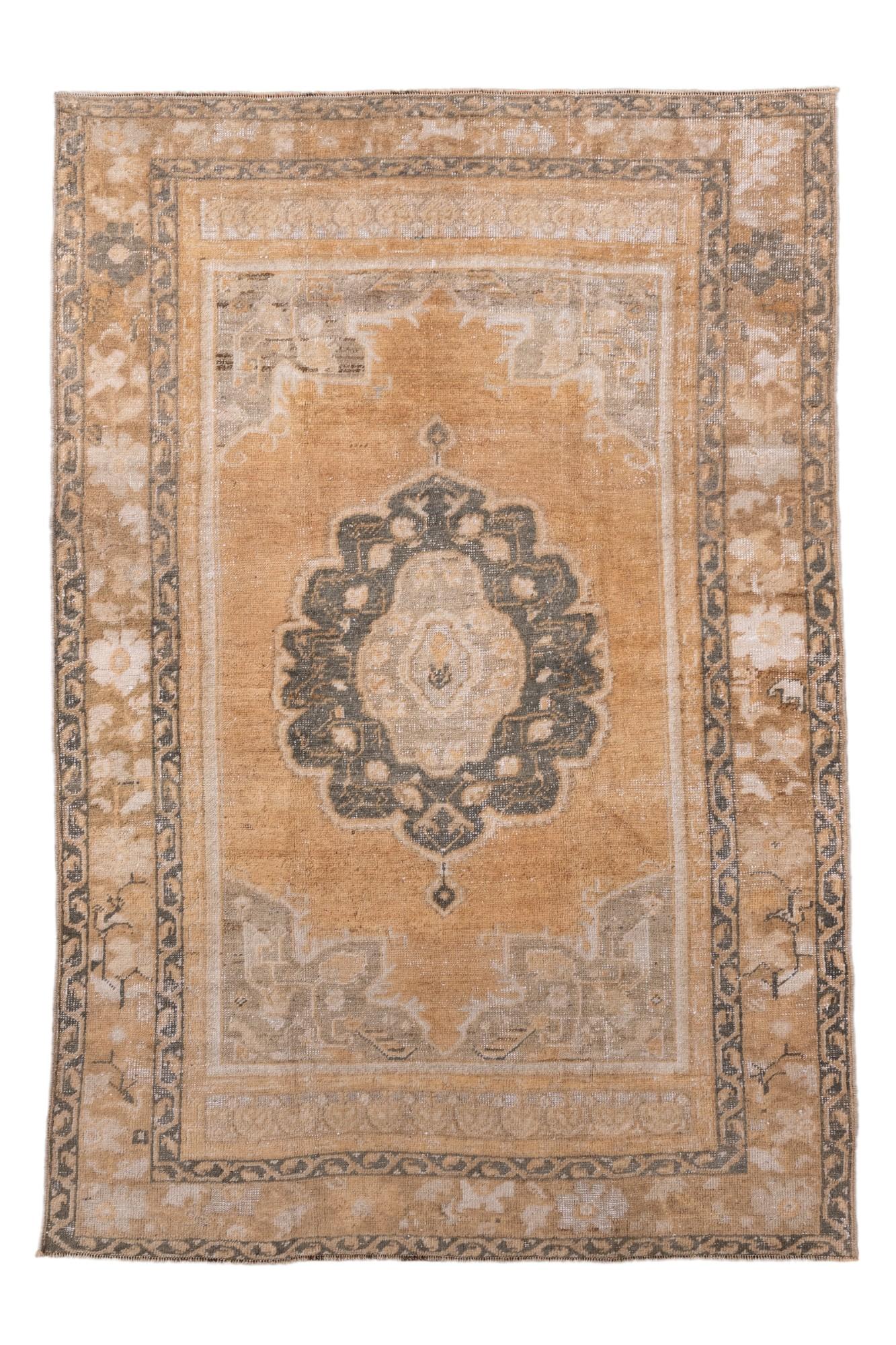 Ce tapis Oushak vintage, tissé à la main dans l'ouest de la Turquie, présente un champ d'or de blé lumineux et un délicat médaillon central en gris argenté et ivoire. Cette pièce met en valeur l'élégance classique du design Oushak turc - des