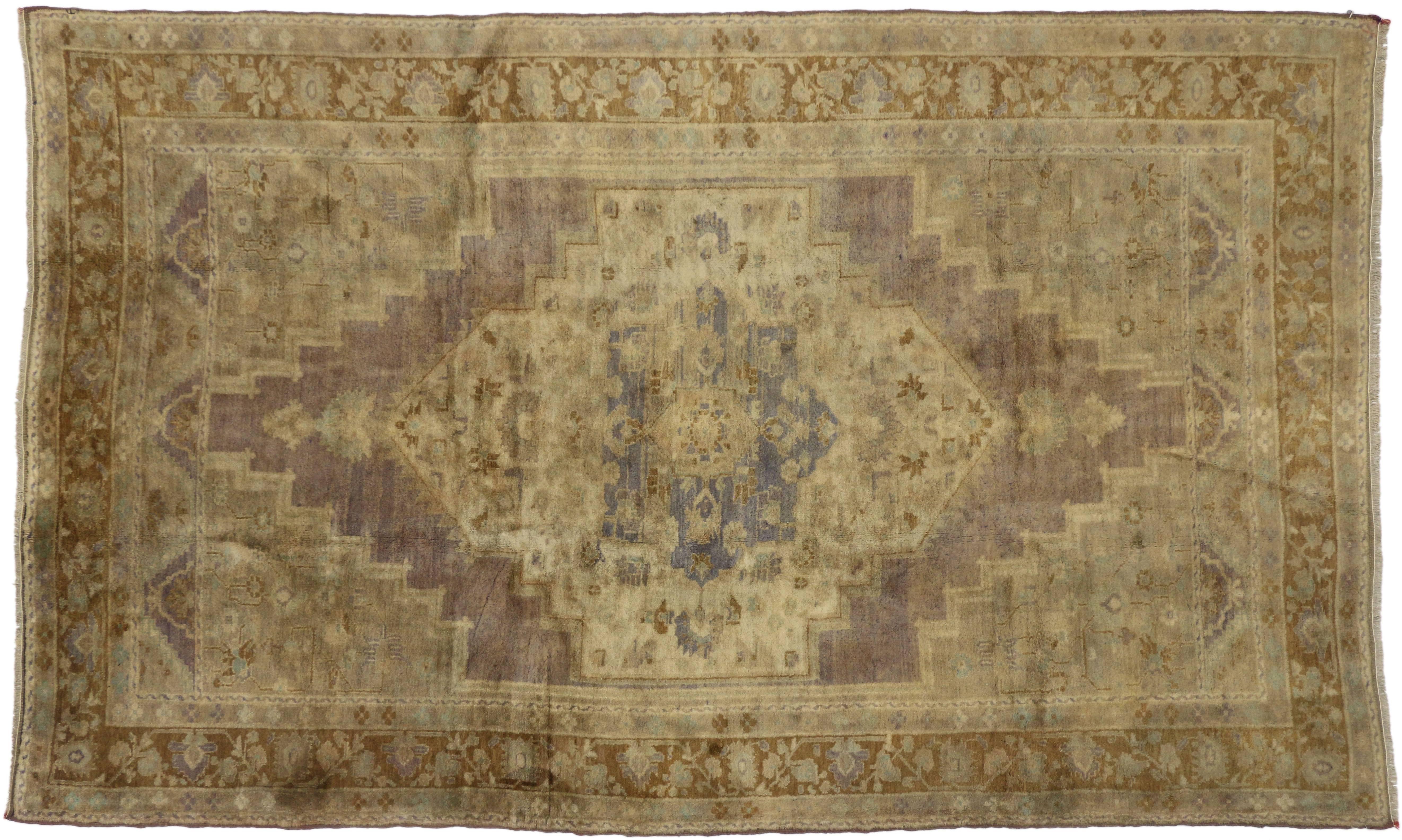 74113, a vintage Turkish Oushak in traditional style. This hand-knotted wool vintage Oushak gallery rug features a central medallion placed on a larger lozenge of faded mocha, anchored with palmettes to either end. The large lozenge is centered on a