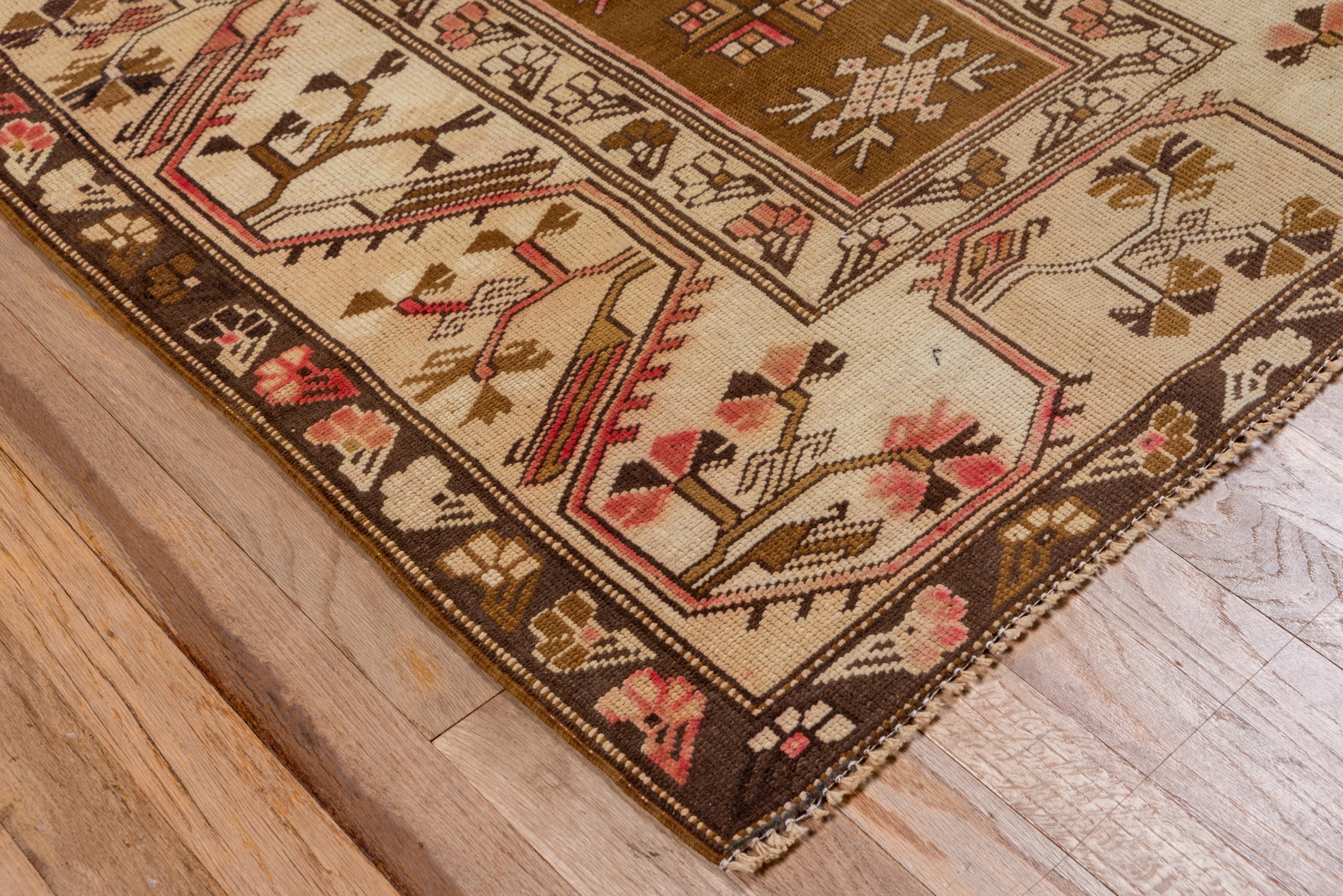 From westernmost Turkey, this prayer design scatter shows a pointed camel and ivory field with detached stylized floral elements, cream spandrel panel, and a straw border with a broad trapezoidal meander enclosing carnations and other Ottoman