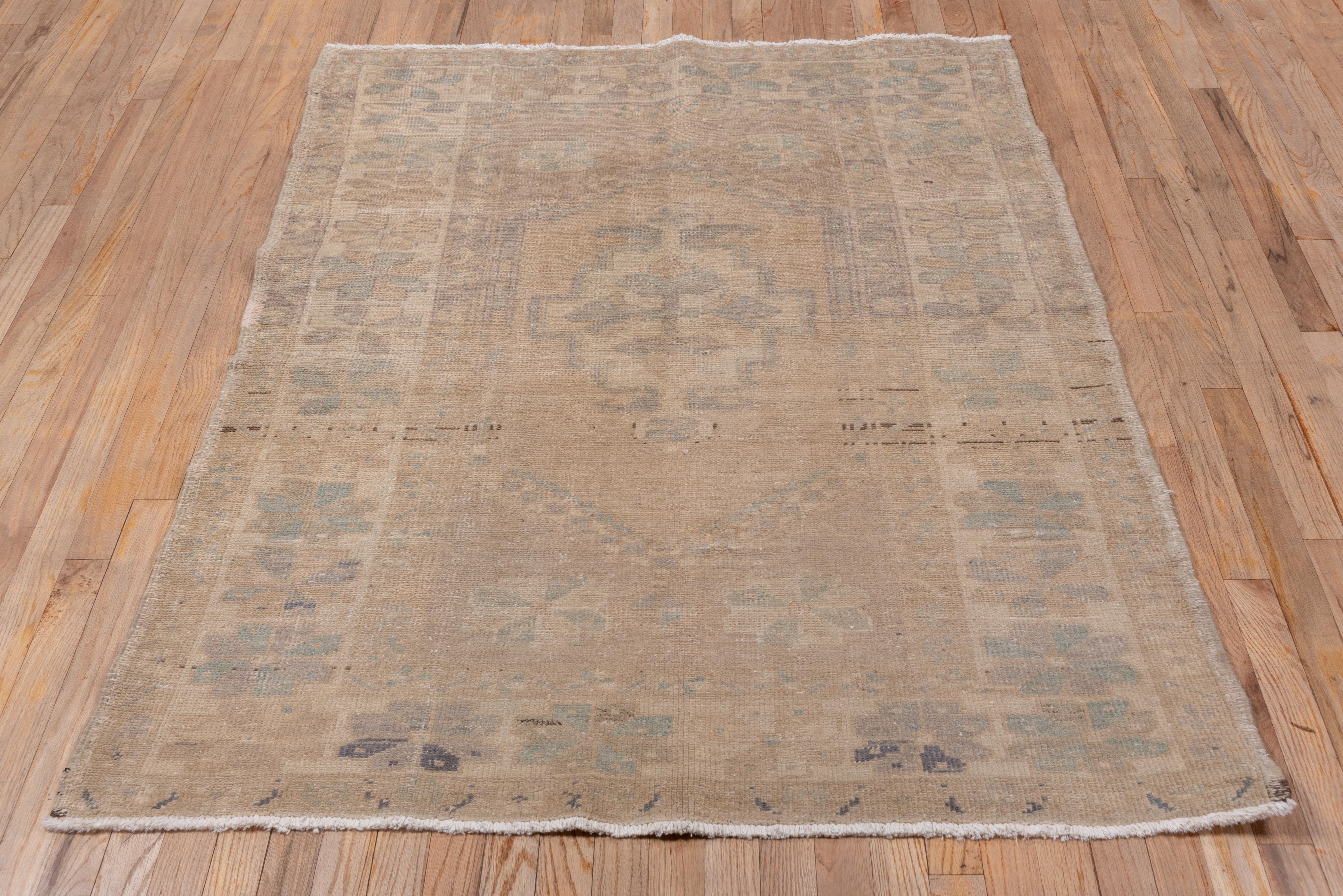 A light tone-on-tone scatter with a few dark brown abrash accents, this coarsely knotted village scatter has a sand stepped medallion with a cruciform palmette center, set within a border system including a wide sand band with large squared-off
