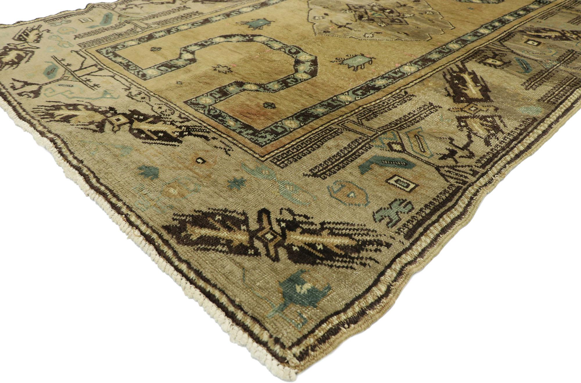 52765, vintage Turkish Oushak rug with Late Victorian style. This hand knotted wool vintage Turkish Oushak rug features a small taupe colored cusped medallion dotted with Anatolian symbols on an abrashed tan field. A dark coffee colored band