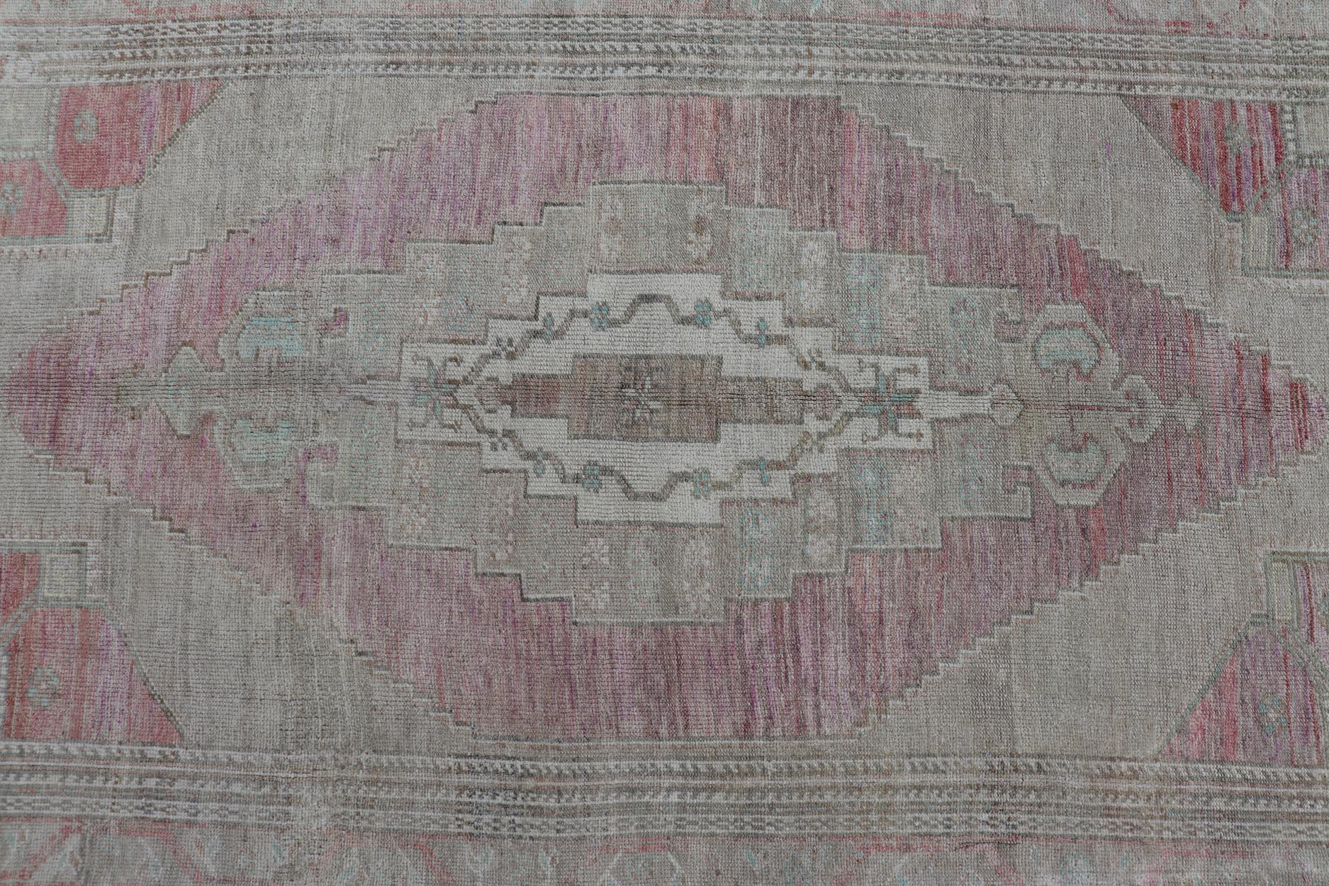Measures: 5'7 x 9'3 

This vintage Turkish Oushak perfectly displays the craftsmanship of this time. The color palette is completely muted, with shades of taupe, camel, pink, blue, teal, magenta, and gold. The border displays a classic medallion