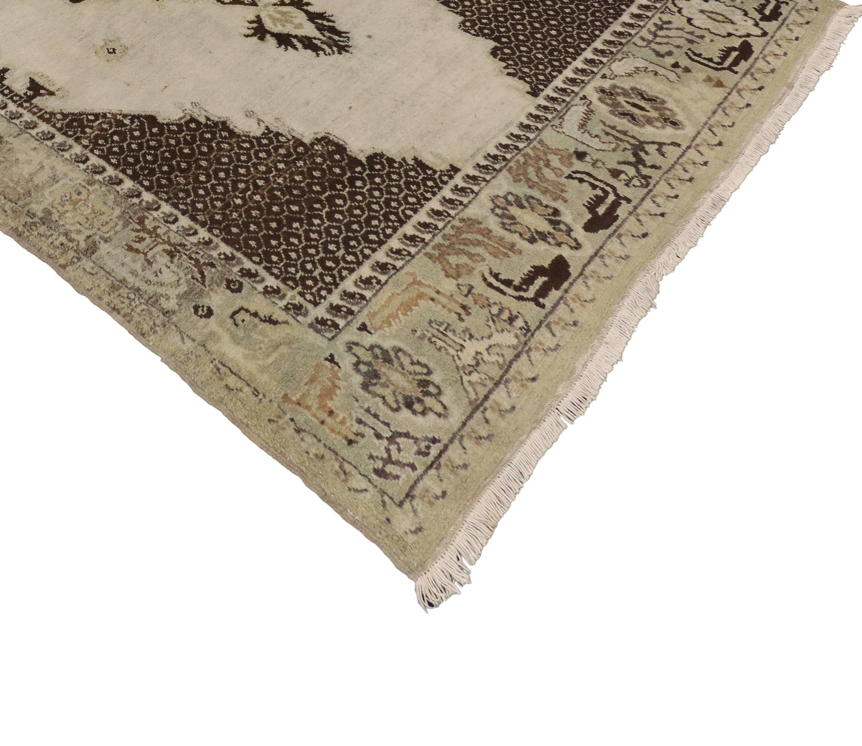 74123, a vintage Oushak rug with medallion and corner design. This hand-knotted wool vintage Turkish Oushak rug features an ornate center medallion bordered with a scrolled vine pattern, anchored by two palmettes. This intricate medallion floats on