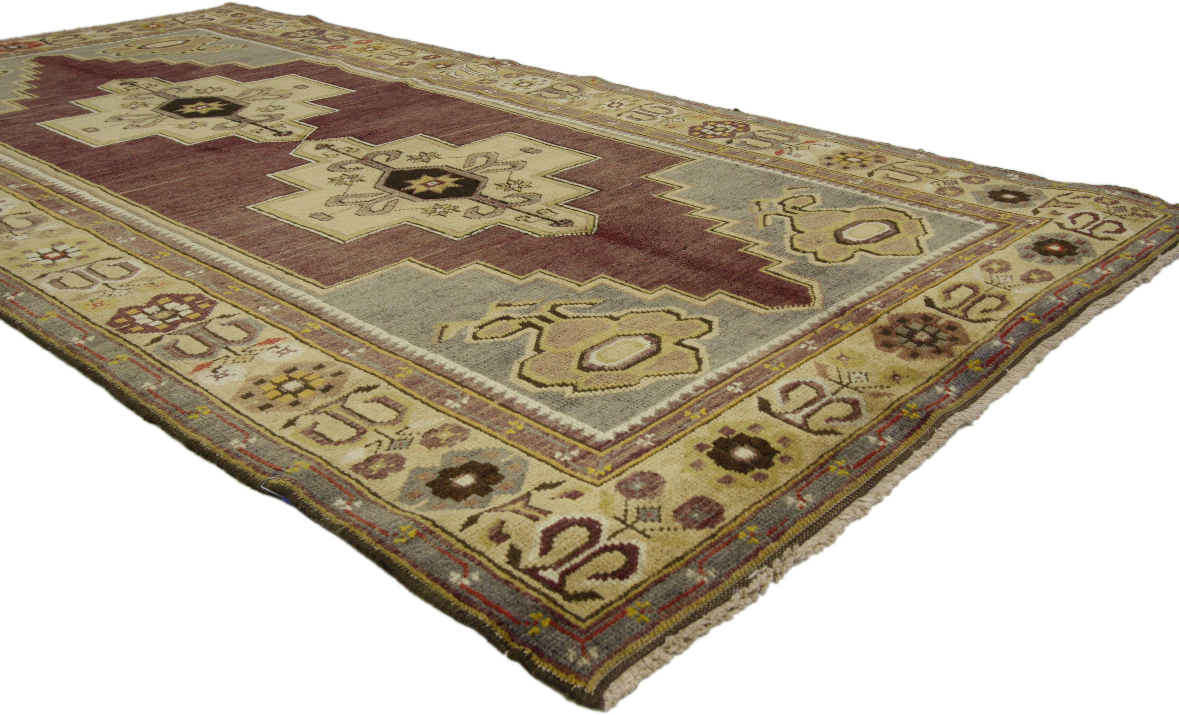 Vintage hand-knotted wool Turkish Oushak rug with traditional modern style featuring a double geometric medallion in an open abrashed field surrounded by a tribal motif border. Color palette consists of plum, gray and beige. Perfect for a hall or