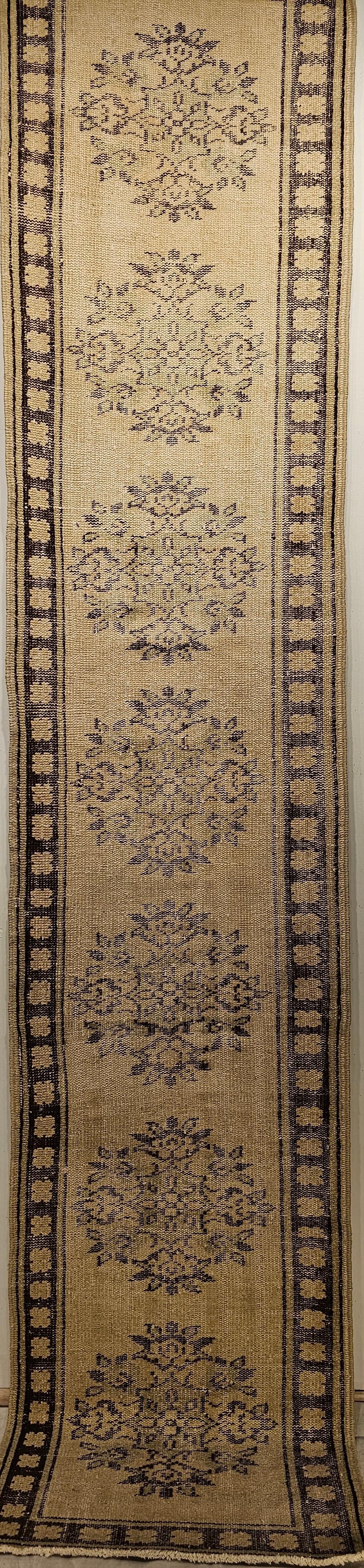 A vintage Turkish Oushak runner from the early 1900s in beautiful earth tone colors. The Turkish Oushak runner has a multiple medallion design set in an ivory color field.   The medallions are in brown and sage green colors.  The narrow border is