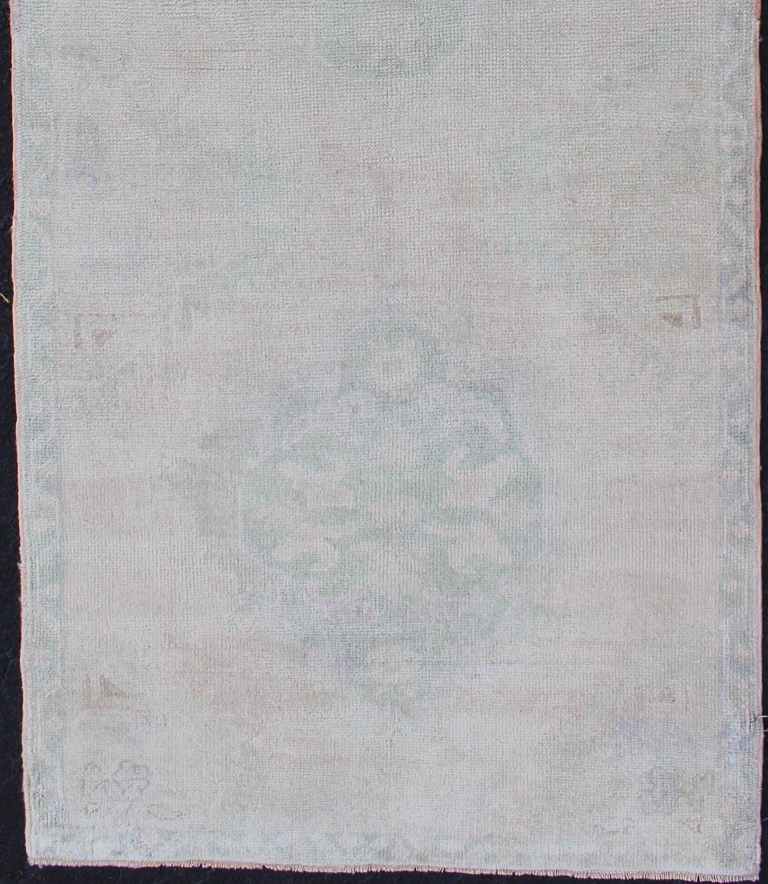 Oushak vintage rug from Turkey with tri-medallion design, rug tu-mtu-4911, country of origin / type: Turkey / Oushak, circa 1940.

This vintage Turkish Oushak rug features a multi-medallion design flanked by floral motifs and an overall faded