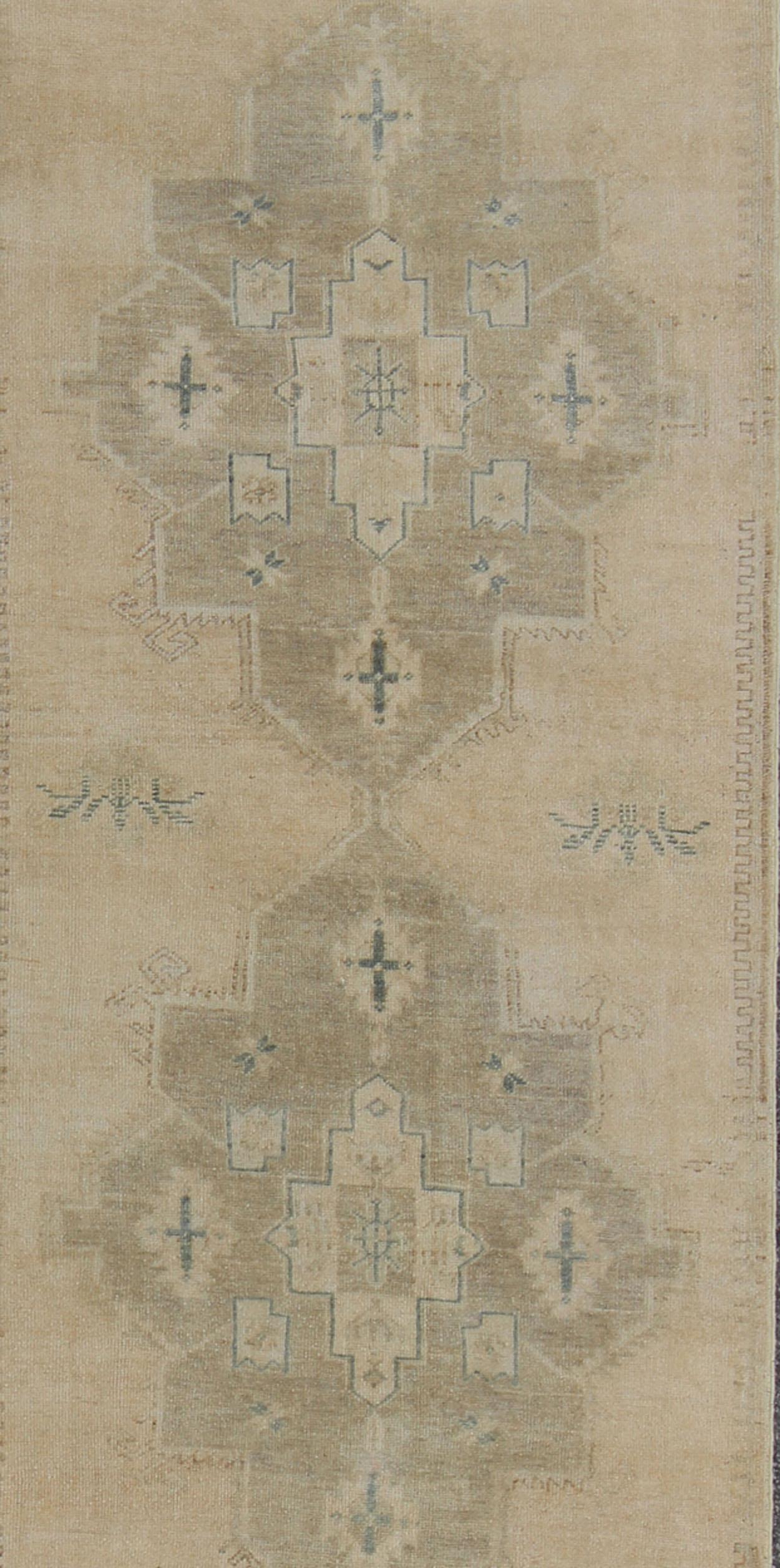 Measures: 3'8 x 11'1 
This vintage Oushak carpet from mid-20th century Turkey features a multi-medallion design in the central field enclosed within a repeating border. This rug is rendered in neutral colors, with medallions in taupe, cream and