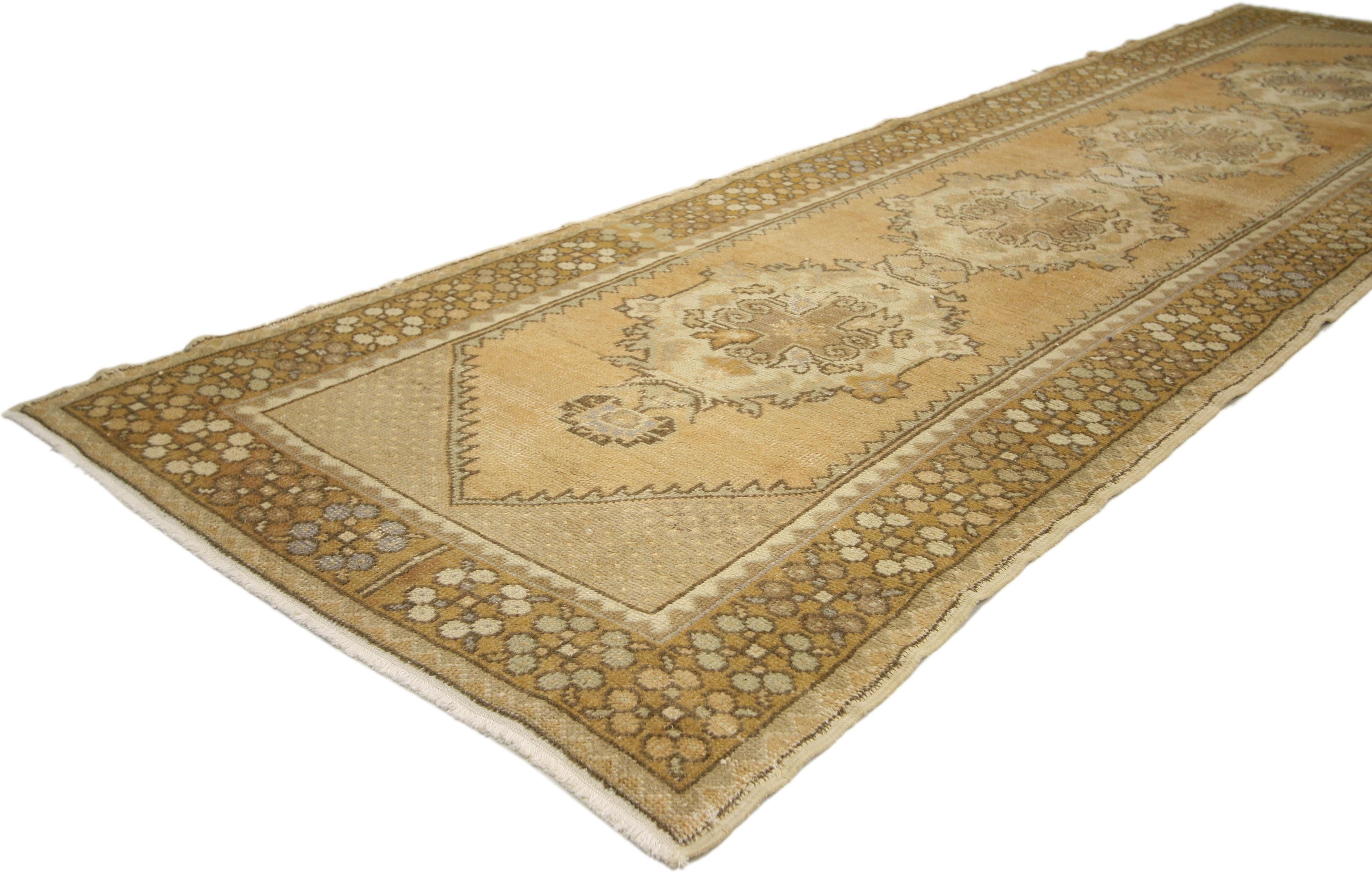 50230, a vintage Turkish Oushak rug runner. This vintage Turkish Oushak runner in warm colors features four intricate connected floral medallions, each with a cruciform with a gul to the center in neutral shades of the desert terrier; sable, sand,