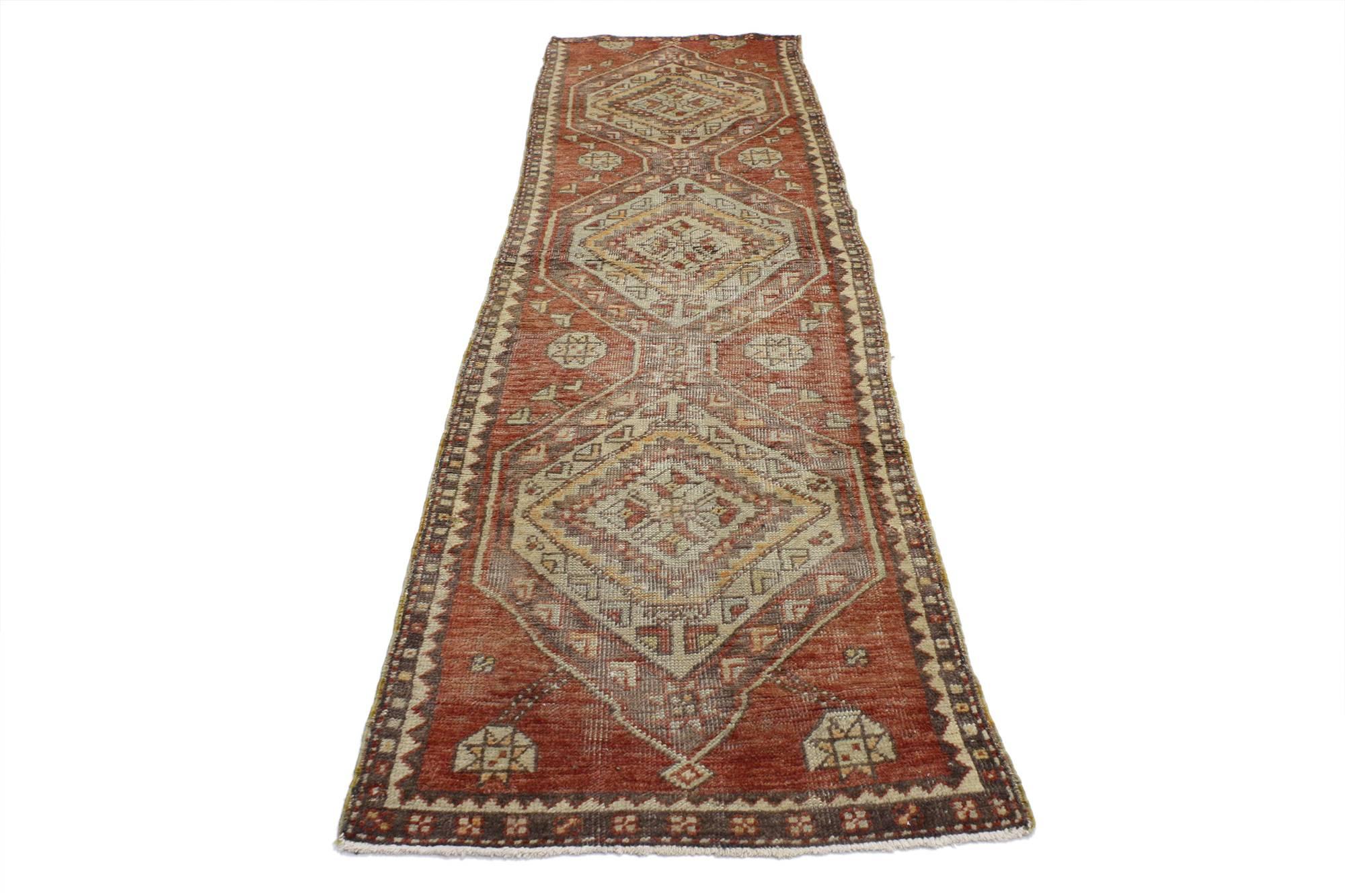 52087, vintage Turkish Oushak runner, narrow hallway runner. This hand knotted wool vintage Turkish Oushak runner features three connected hexagonal pole medallions spread across an abrashed brick red field. Superimposed concentric diamonds with