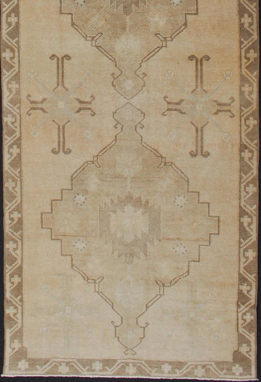 vintage Turkish Oushak runner in neutral colors with medallions in taupe, blue and light brown. rug/TU-ALK-4873. Vintage Oushak runner
This vintage Oushak carpet from mid-20th century Turkey features a multi-medallion design in the central field.