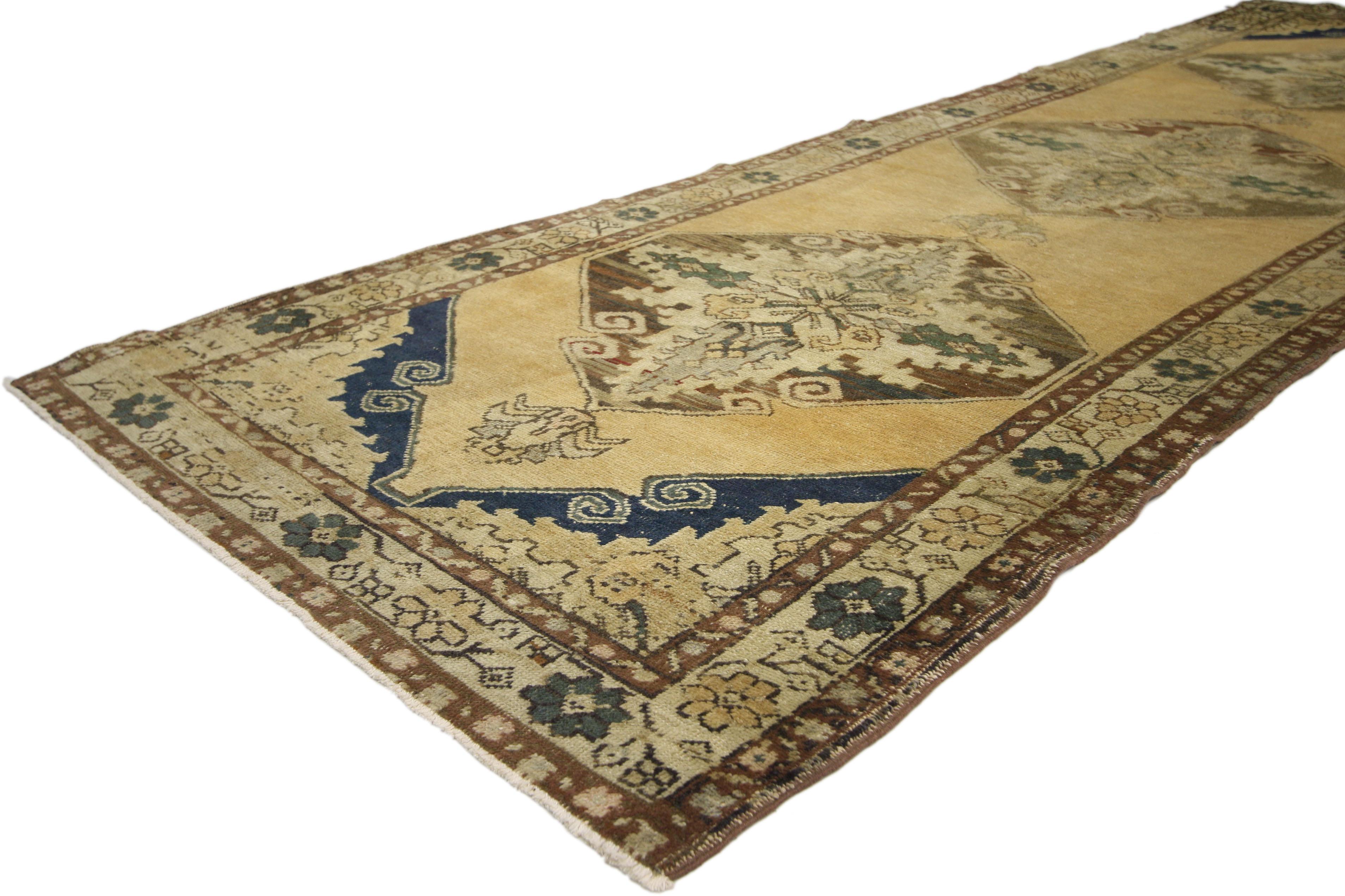 This vintage Turkish Oushak carpet runner with Modern style features three geometric medallions with cartouche finials in an open, abrashed golden-beige field. Resplendent with elements of modern design, this vintage Oushak runner handsomely