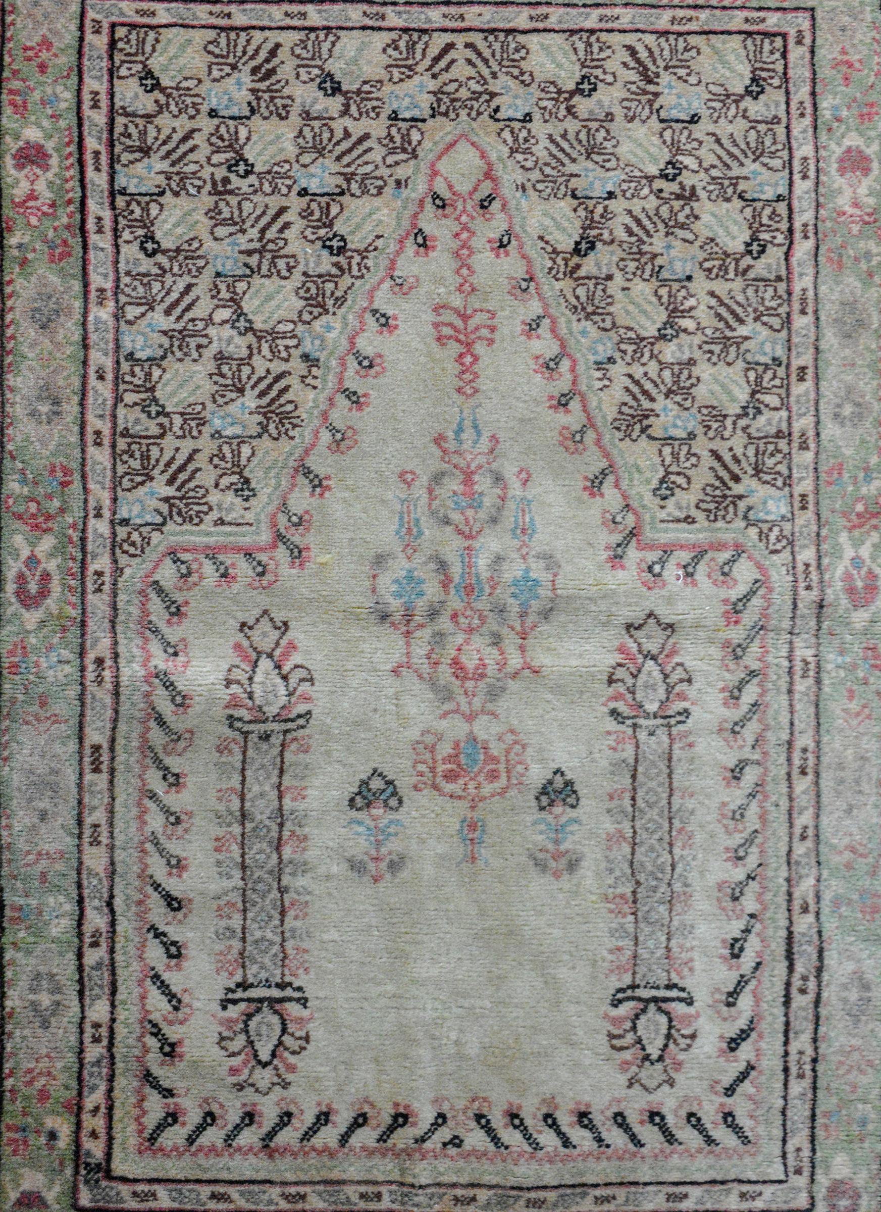 A vintage Turkish prayer rug with a luted color palette containing cream, pale green, pale indigo, and cranberry colors. The border is wonderful with several wide and thin floral partnered stripes.