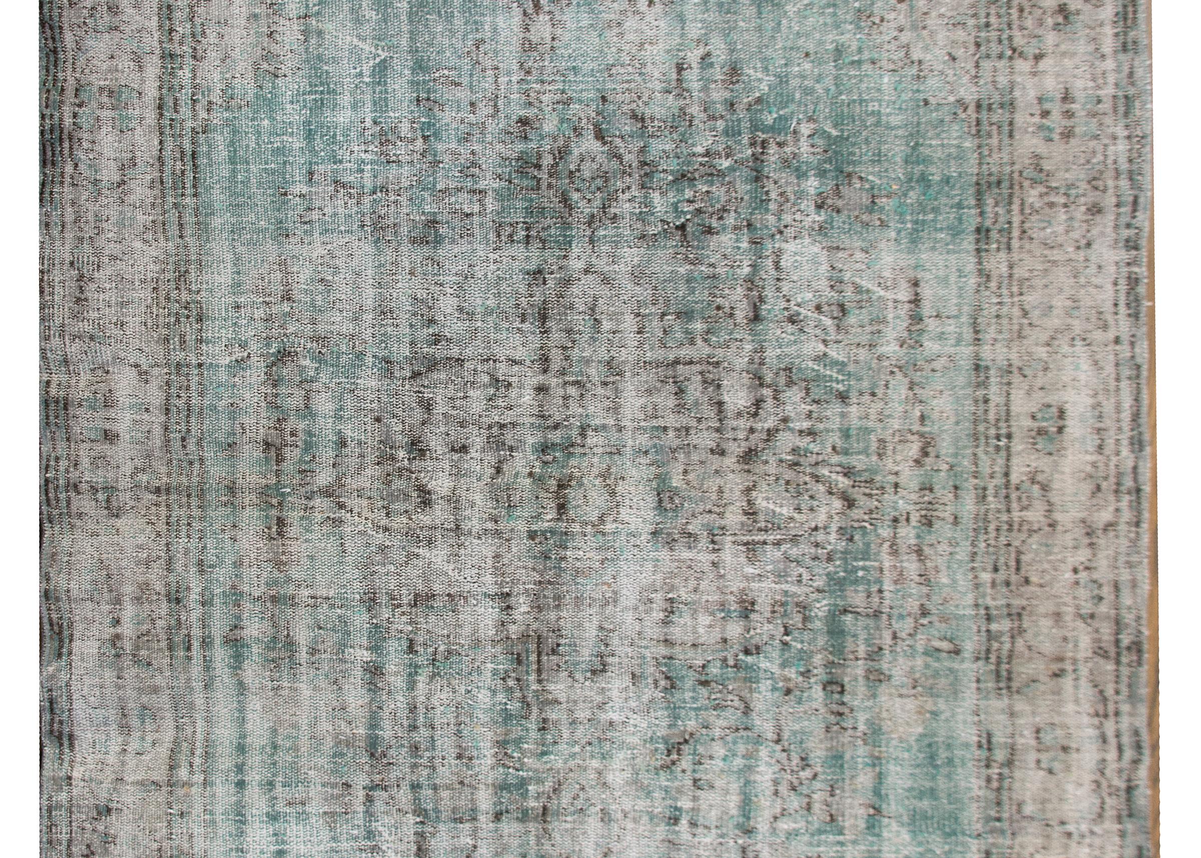 A wonderful vintage Turkish rug with a large central floral medallion living amidst a turquoise field, and surrounded by a wide floral patterned border, and all stonewashed to give it an antiqued feel.