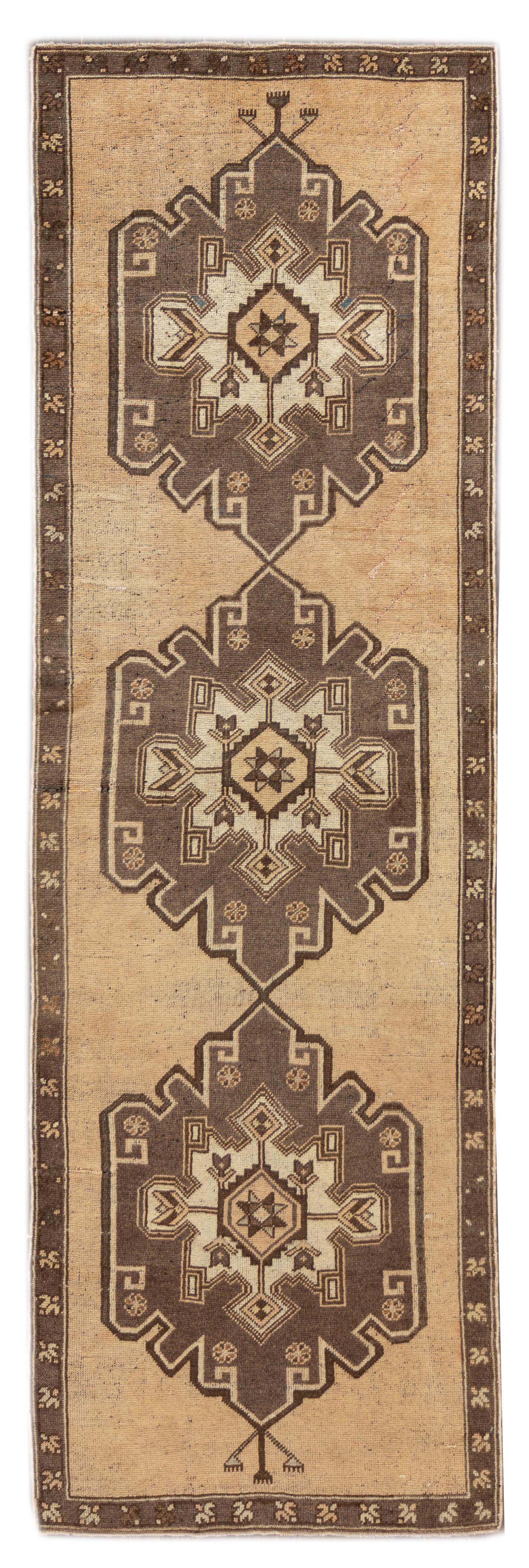 A vintage hand knotted wool Turkish runner rug with a tan field and multi-medallion design. This rug measures 3'3