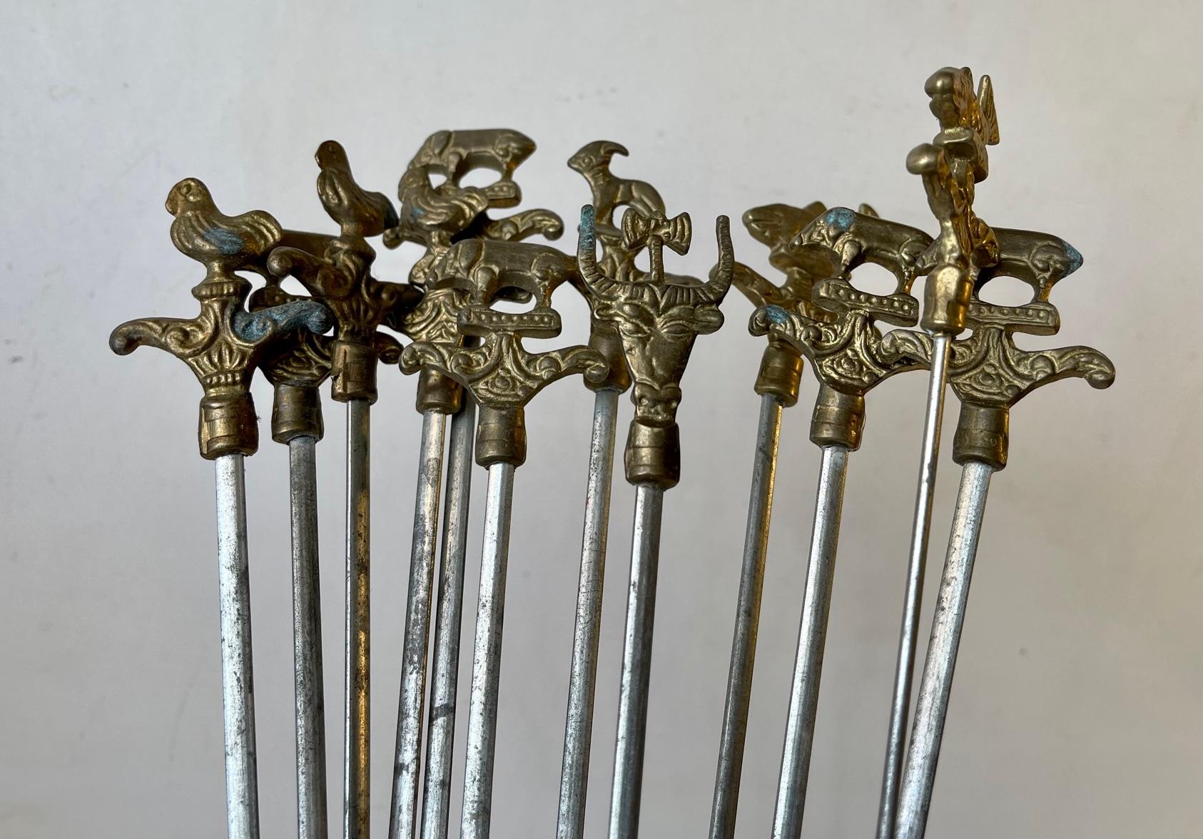 A set of 12 (+1) original Turkish sis kebab skewers. Made from practical flat stainless steel topped with handles of ornamented animals in brass. This set was manufactured by Serer in Istanbul Turkey during the 1960s or 1970s. The length of the 12