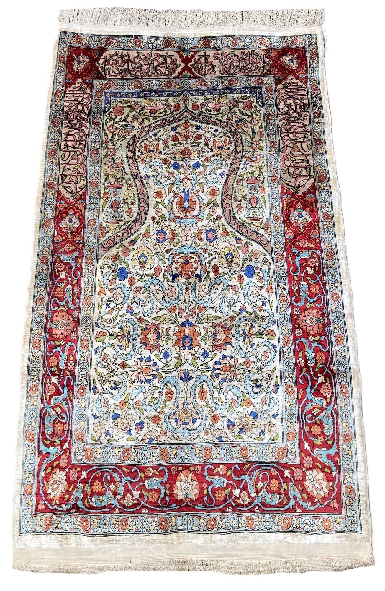 A beautiful silk Turkish rug, hand woven in Hereke (approximately 60 kms south-east from Istanbul) circa 1980s with a traditional ‘Mihrab’ design on an ivory field. Very finely woven with 11x11 knots per cm on a silk foundation highlighted with