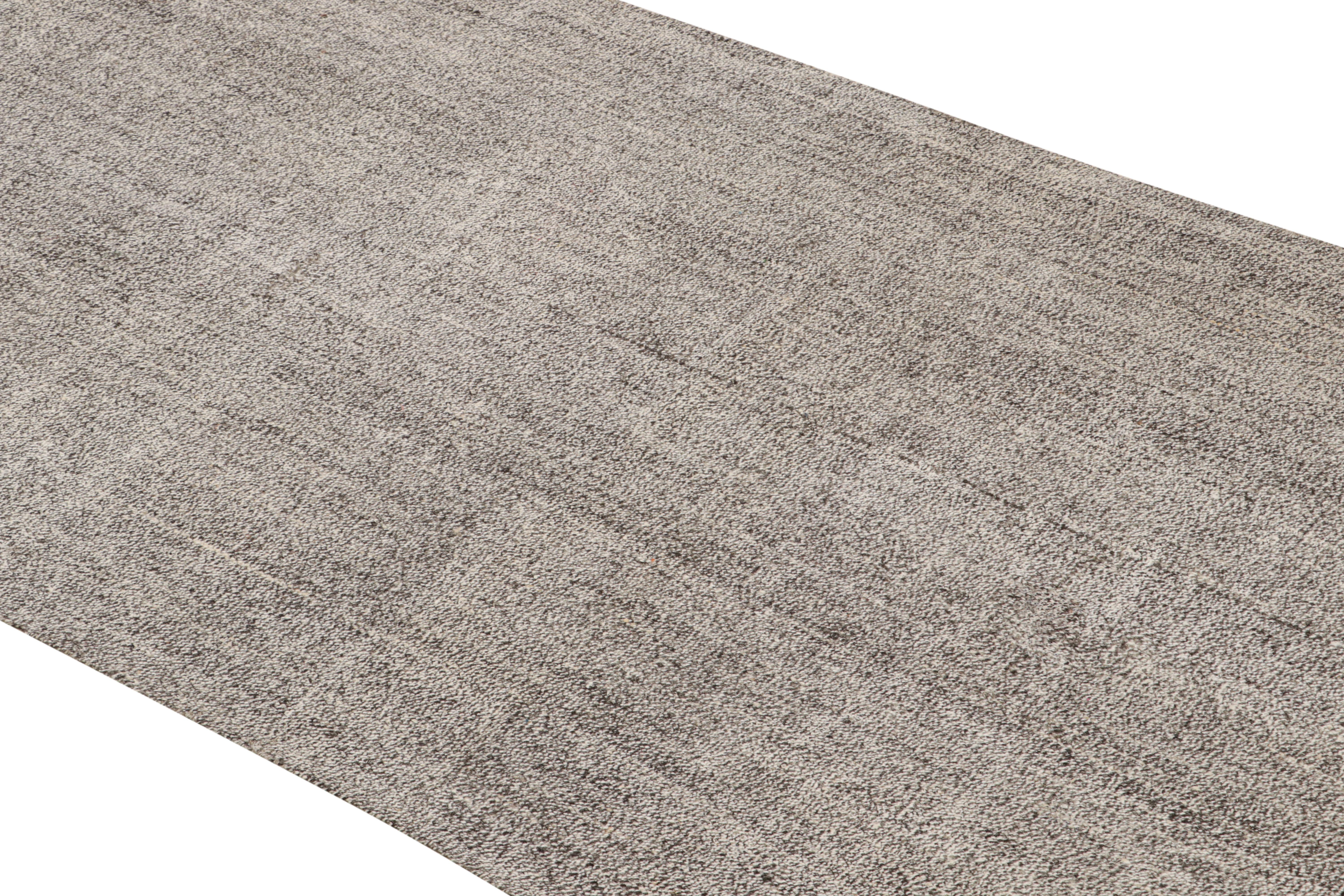 Esta alfombra Kilim vintage de lana, originaria de Turquía en 1960, está tejida en plano en lana de alta calidad con sutiles rayas rectilíneas orientadas verticalmente de colores industriales y metálicos grises y plateados.
  