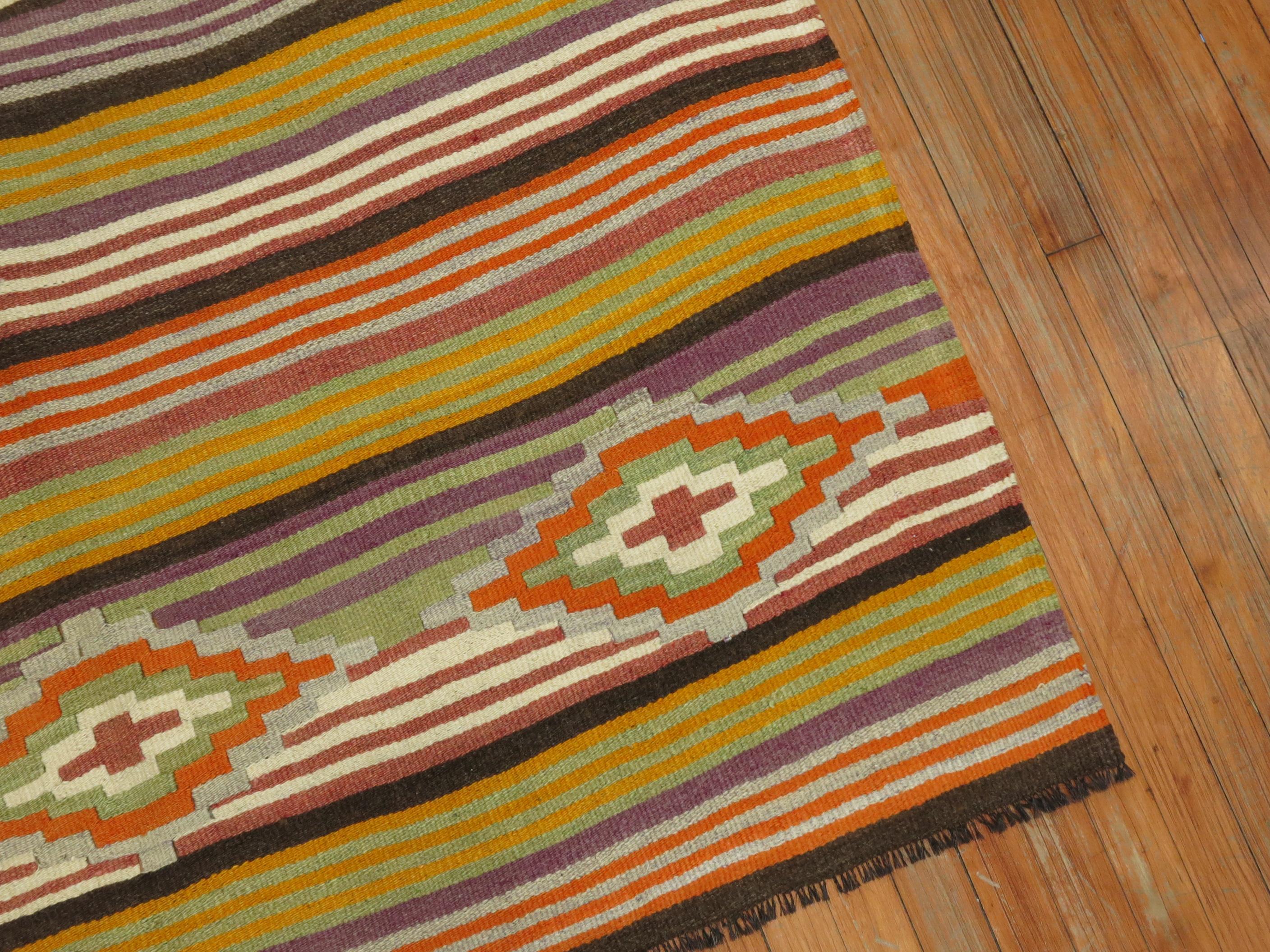 An intermediate size vintage Turkish Kilim with a colorful striped design throughout.
