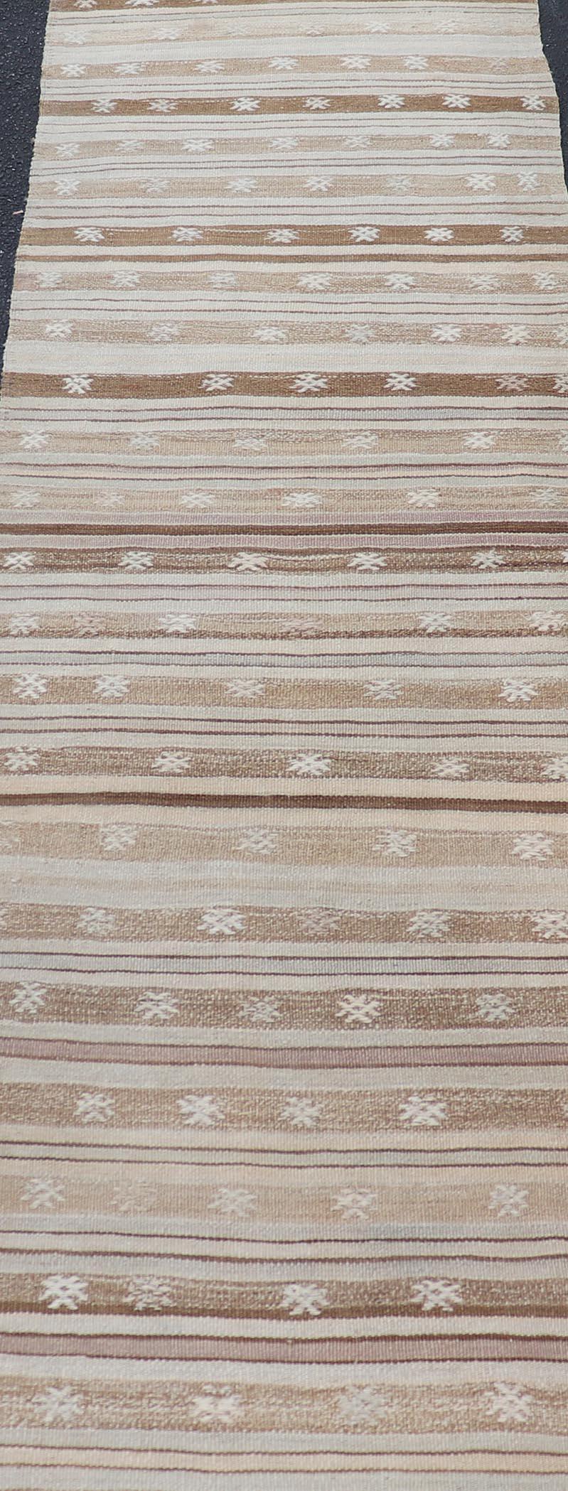Measures: 2'9 x 9'8 This charming vintage Turkish Tribal Kilim runner is an exceptional piece that combines traditional craftsmanship with a warm, neutral color palette. The runner features a series of horizontal stripes in varying shades of beige,