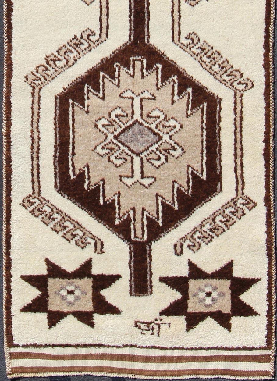 Turkish Tulu vintage Runner with vertical tribal medallion design, rug en-176266, country of origin / type: Turkey / Tulu, circa 1960

This unique Turkish Tulu runner features a bold vertical design of various medallions set atop an cream-colored