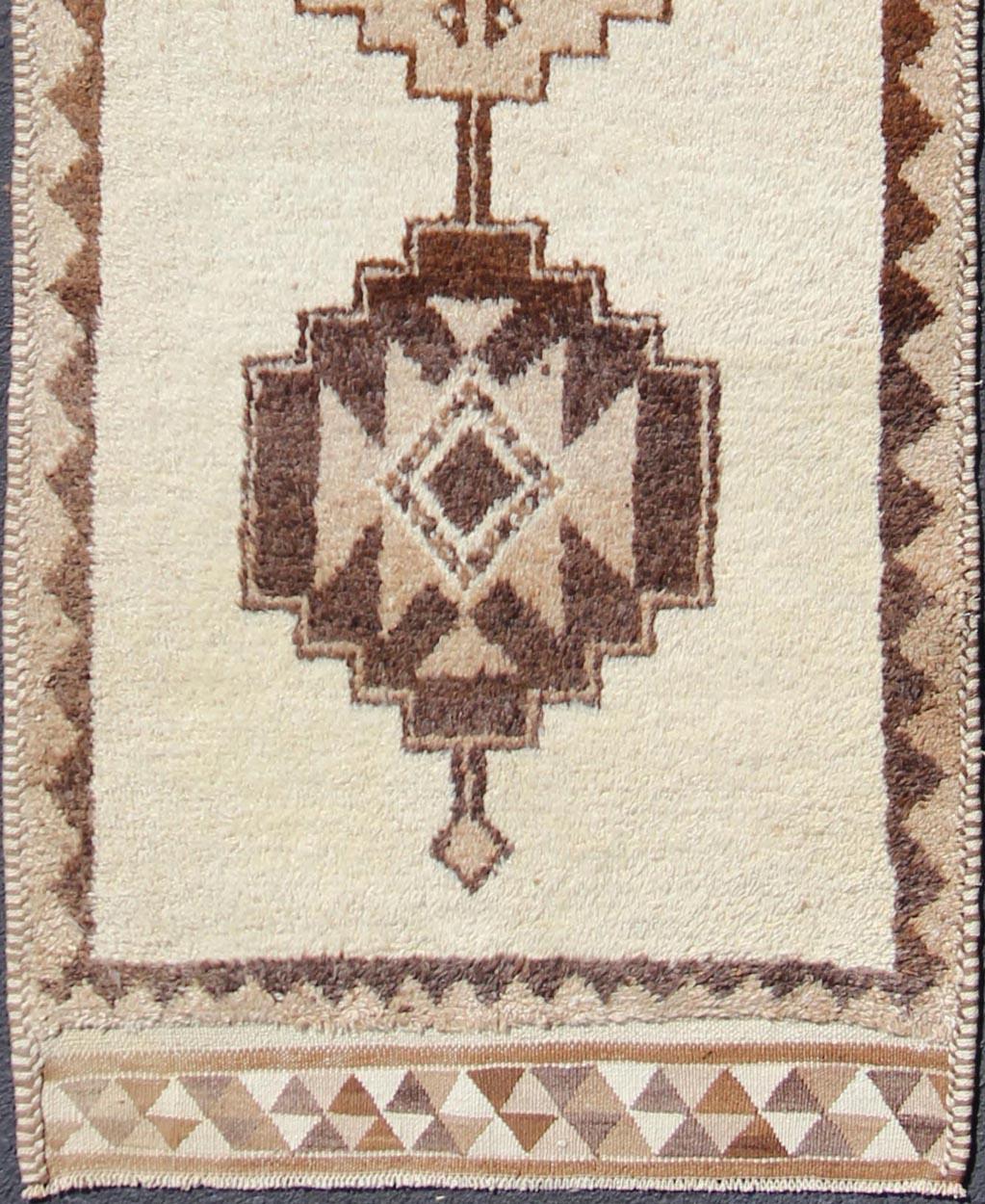 Turkish Tulu vintage runner in earth tones with tribal medallion design, rug en-176285, country of origin / type: turkey / Tulu, circa 1960

This unique Turkish Tulu runner features a vertical design of tribal motifs set atop a cream-colored