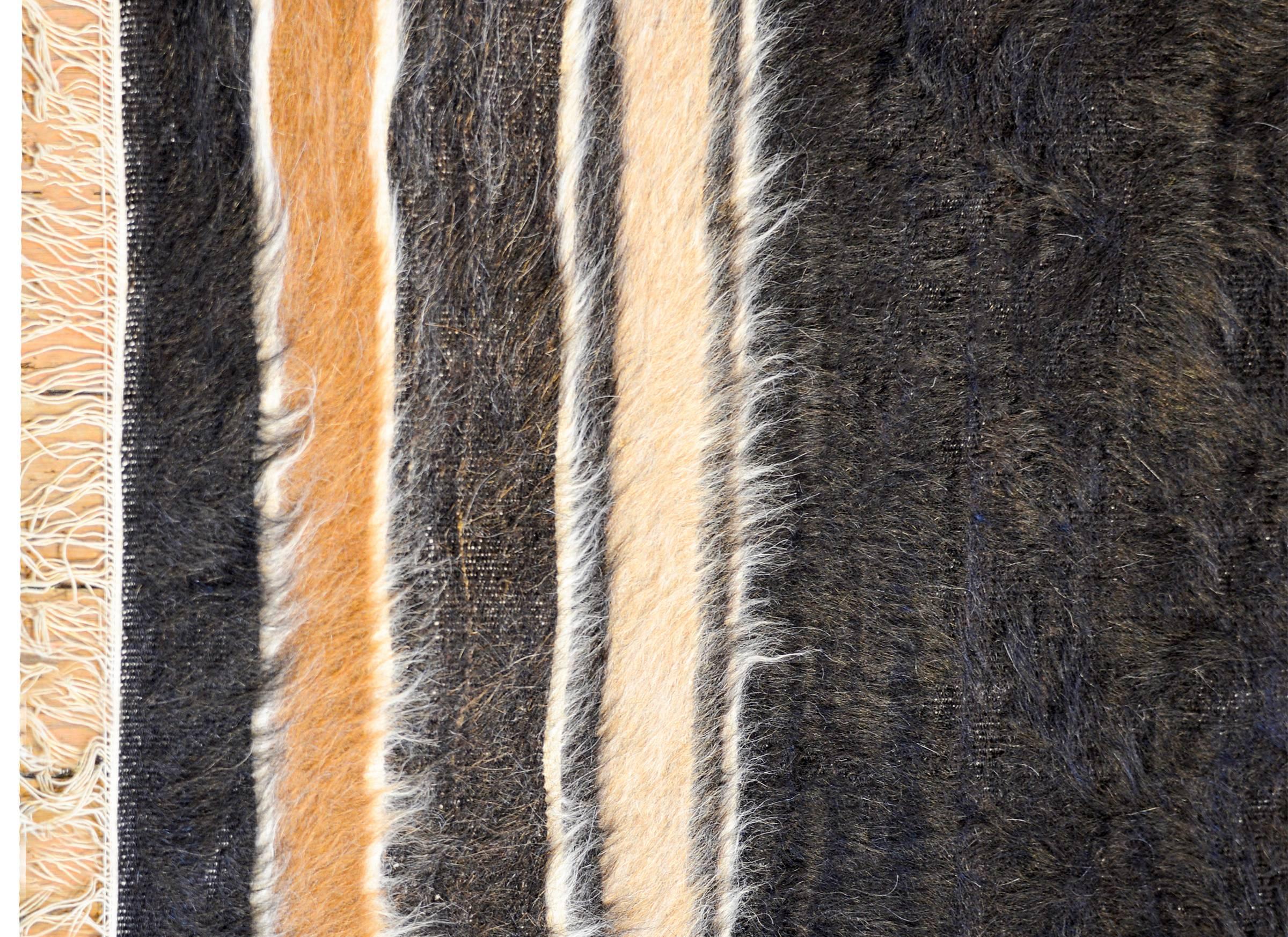 A vintage Turkish Tulu rug with wide central field of black wool, flanked by multiple cream and brown, naturally occurring, colored wool stripes.