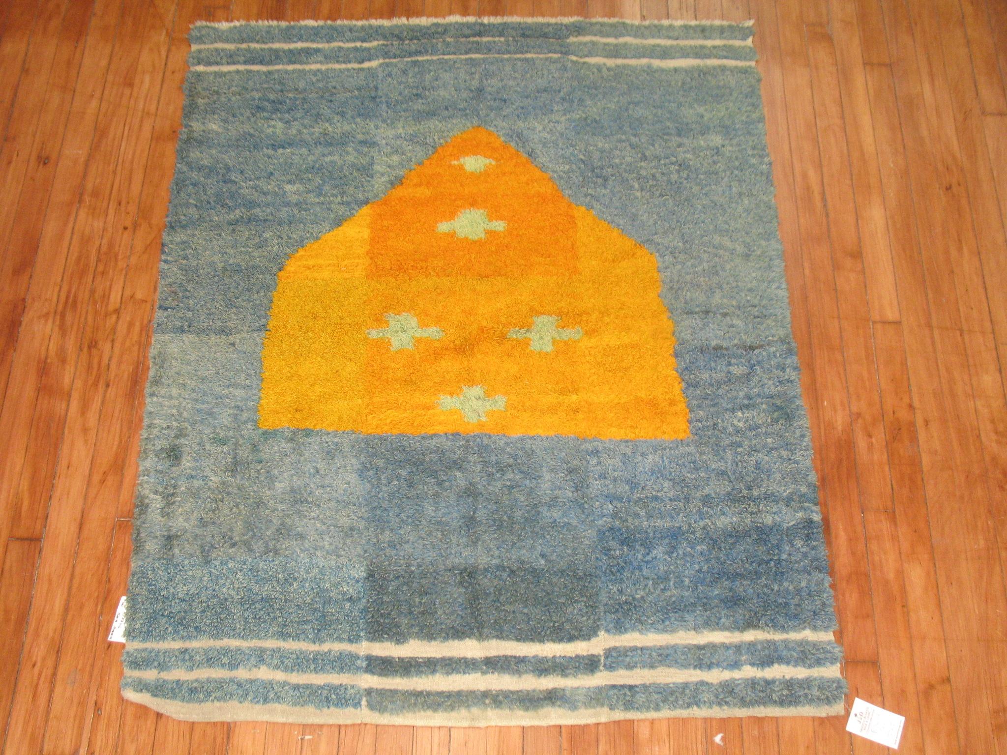 A fun Turkish Tulu rug with an off center citrus color house shaped medallion on blue ground.
