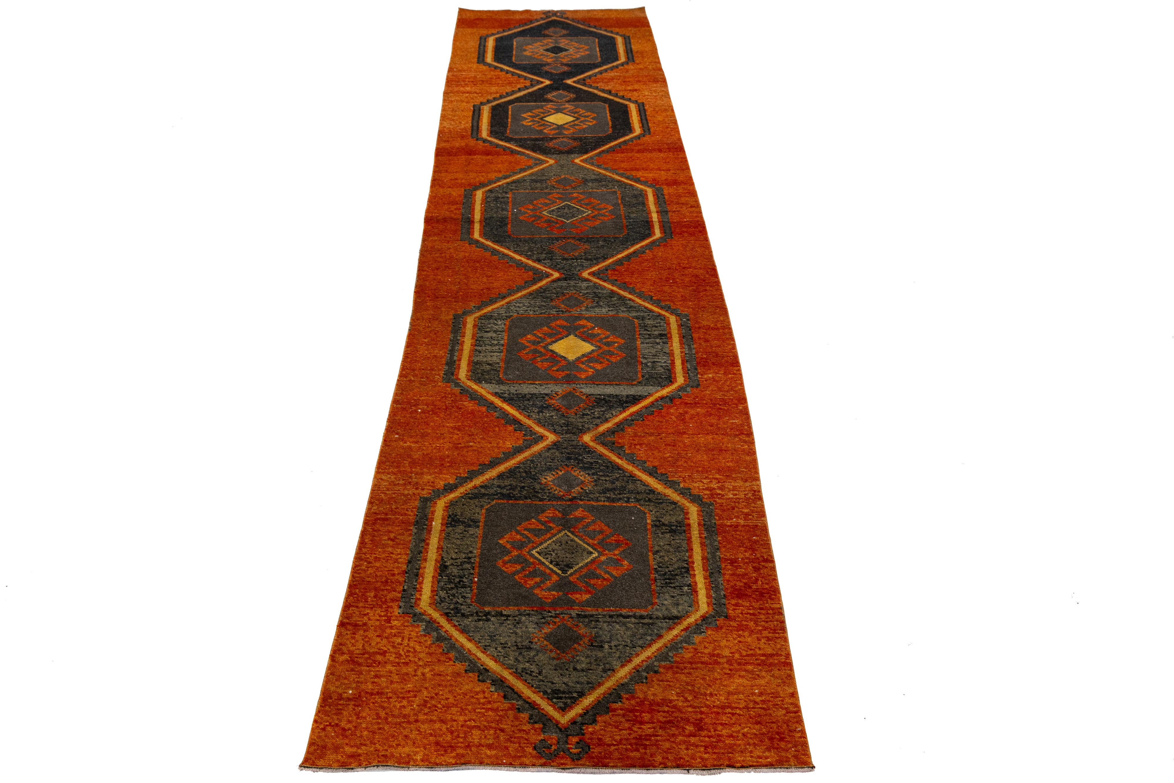 Handwoven in Turkey, this Vintage runner features six bold hexagonal medallions set against a warm reddish-orange field. Crafted from natural wool, its symmetrical layout and earthy palette reflect a modern interpretation of traditional Anatolian
