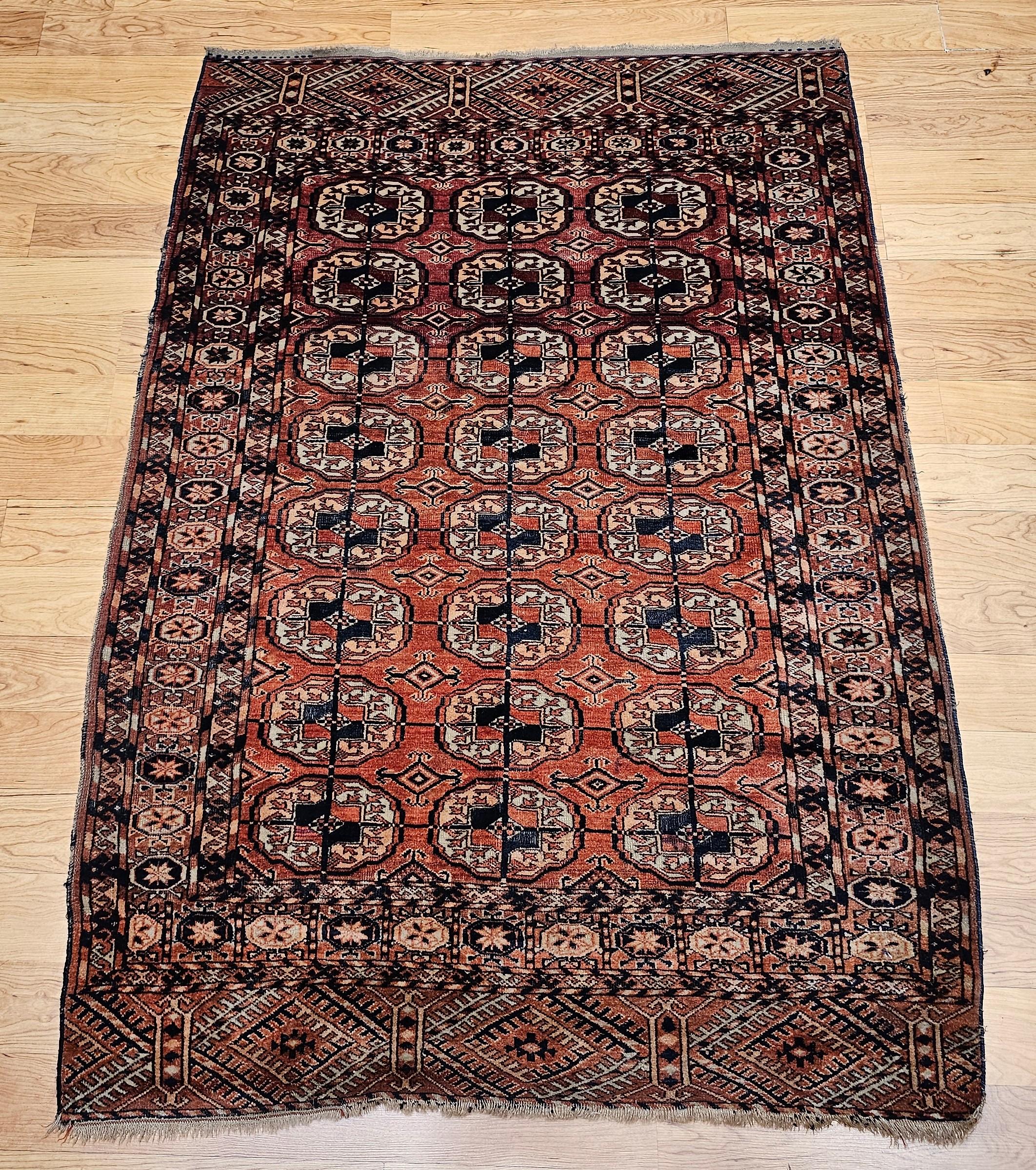 Vintage Turkmen Tekke area rug in an allover small medallion pattern from the early 1900s.  The rug has a beautiful and graceful brick-red background color.  The medallions are in brick-red, navy, yellow, and pink colors.  Rug has a very fine weave