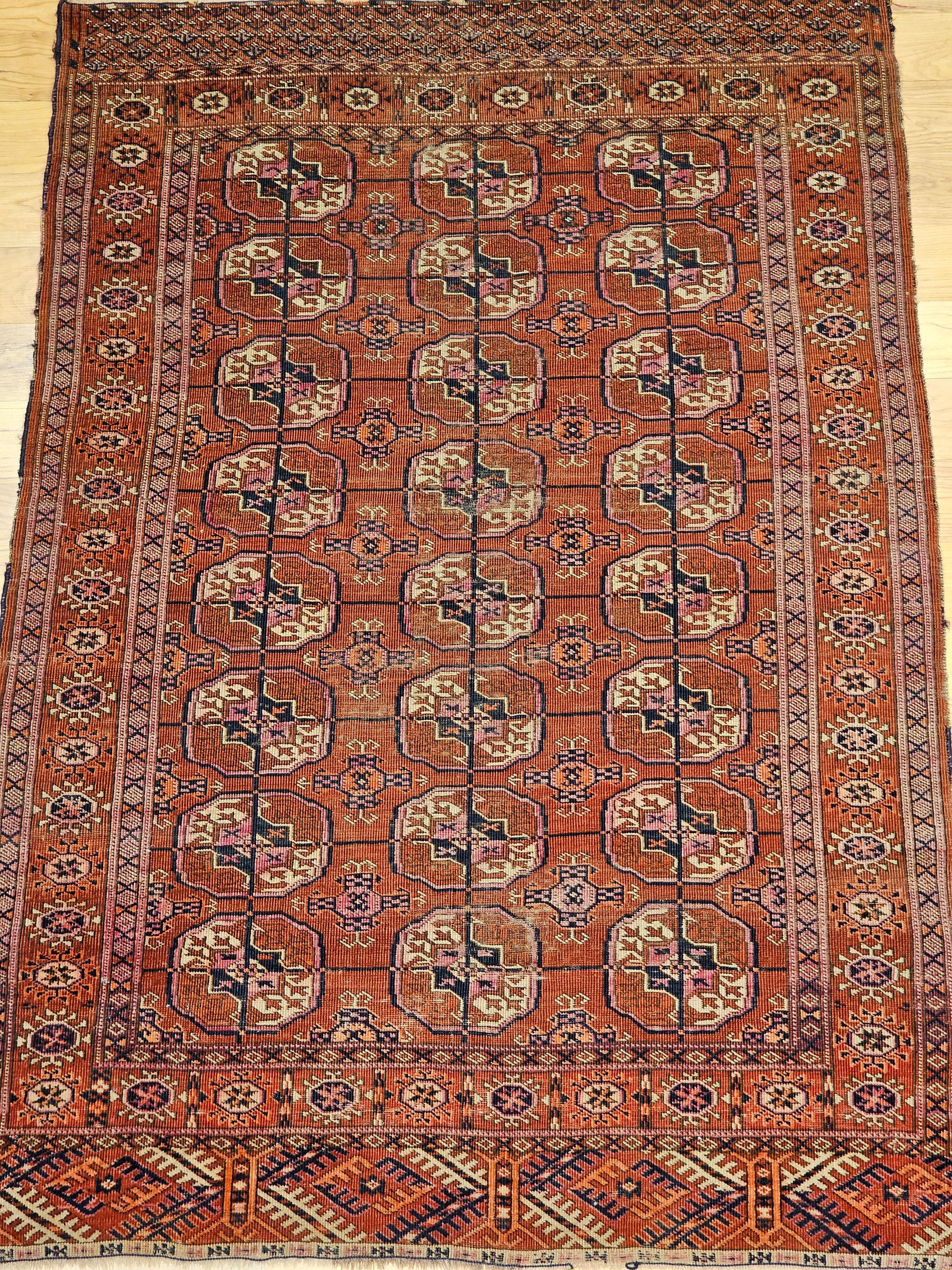 Vintage Turkmen Tekke Teppich in einem allover kleinen Medaillon-Muster aus den frühen 1900er Jahren.  Der Teppich hat eine schöne und anmutige ziegelrote Hintergrundfarbe.  Die Medaillons sind in den Farben ziegelrot, marineblau, gelb und rosa