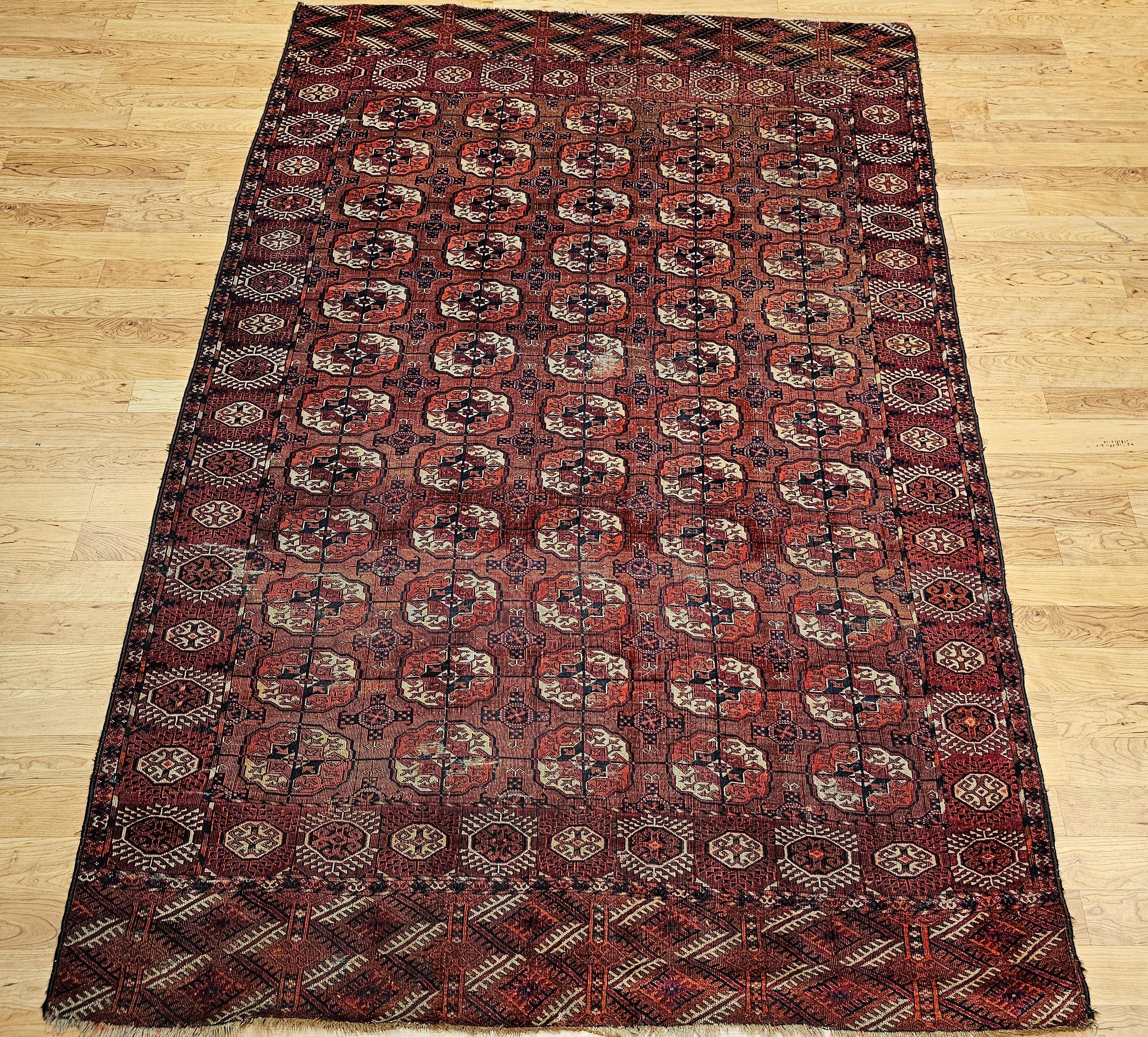 Vintage Turkmen Tekke area room size rug in an allover small “Turkmen Gul” medallion pattern from the late 1800s.  The rug has a beautiful and graceful red background color.  The medallions are in crimson, navy, ivory, and rust.  Rug has a very fine